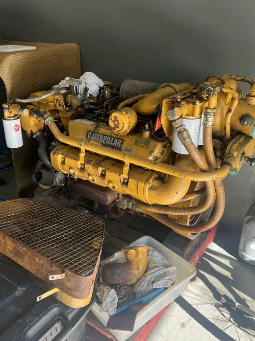 A large yellow Caterpillar industrial engine with pipes and filters, placed on a table in a workshop.