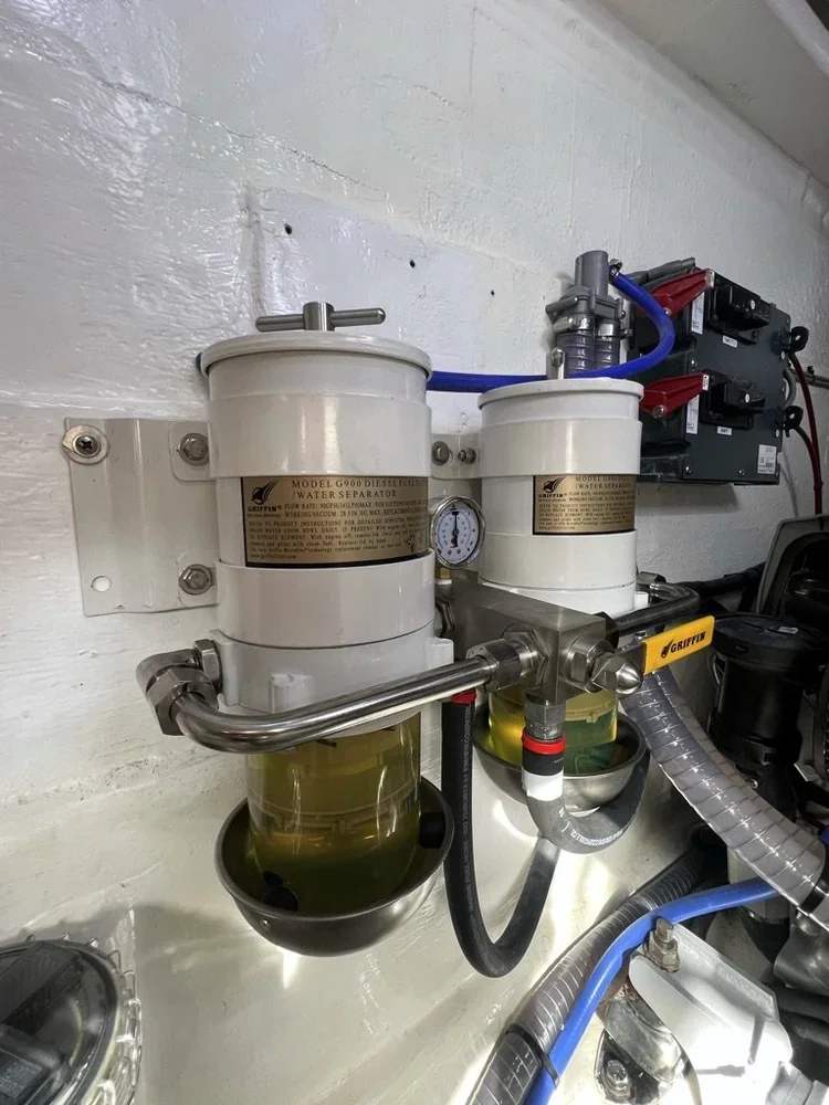 Oil water separator machine connected to pipes, with a pressure gauge and electrical components nearby.