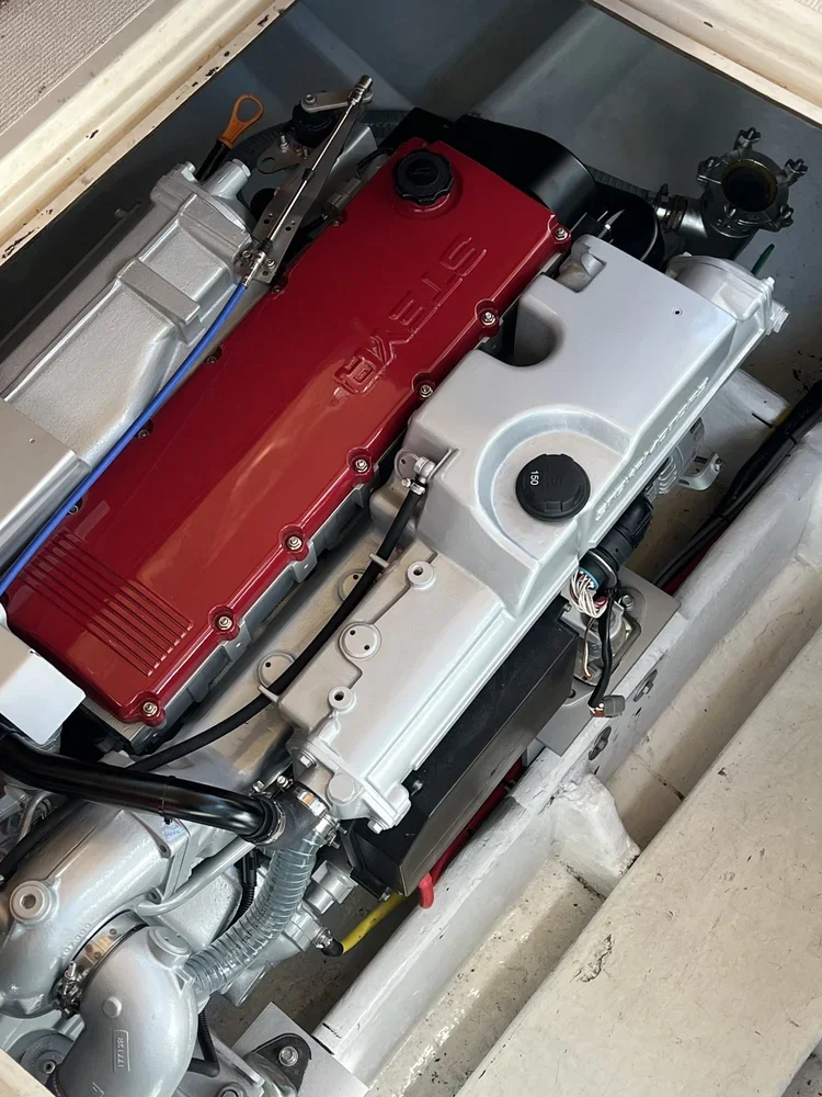 A close-up view of a Tesla electric engine with visible red and silver components, wires, and mechanical parts.