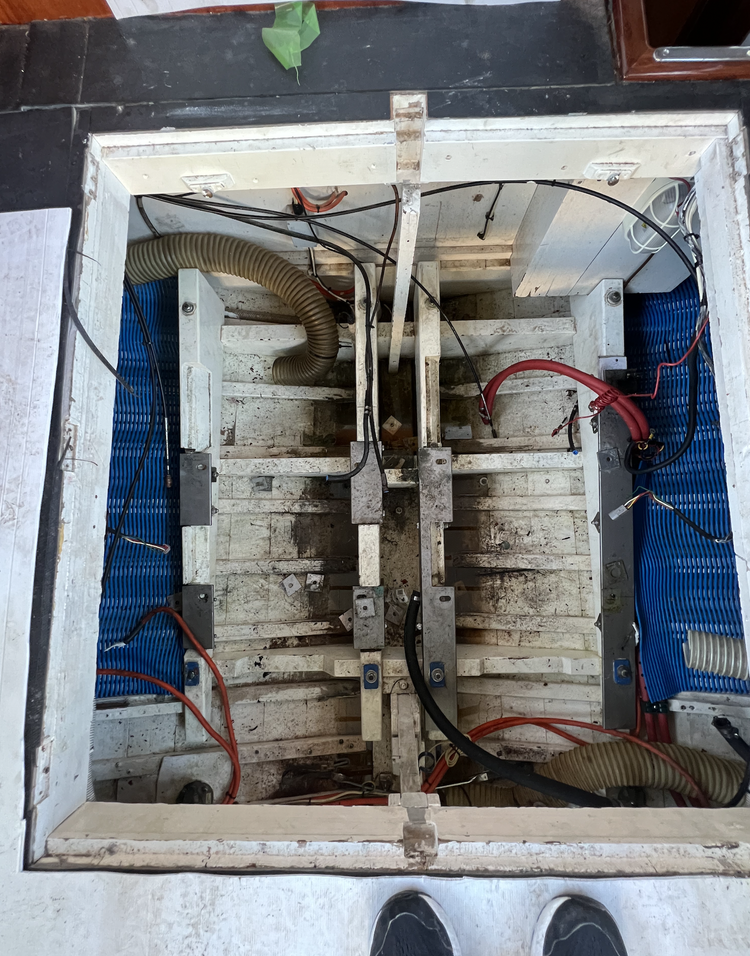 Top-down view of an empty wooden structure with electronic components, wires, tubing, and metal brackets, possibly part of a project or machinery.