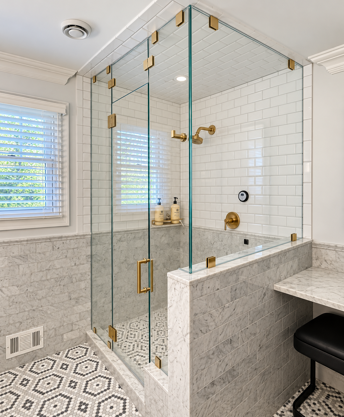 Frameless glass shower enclosure with brass-finish hardware in a white tiled bathroom.