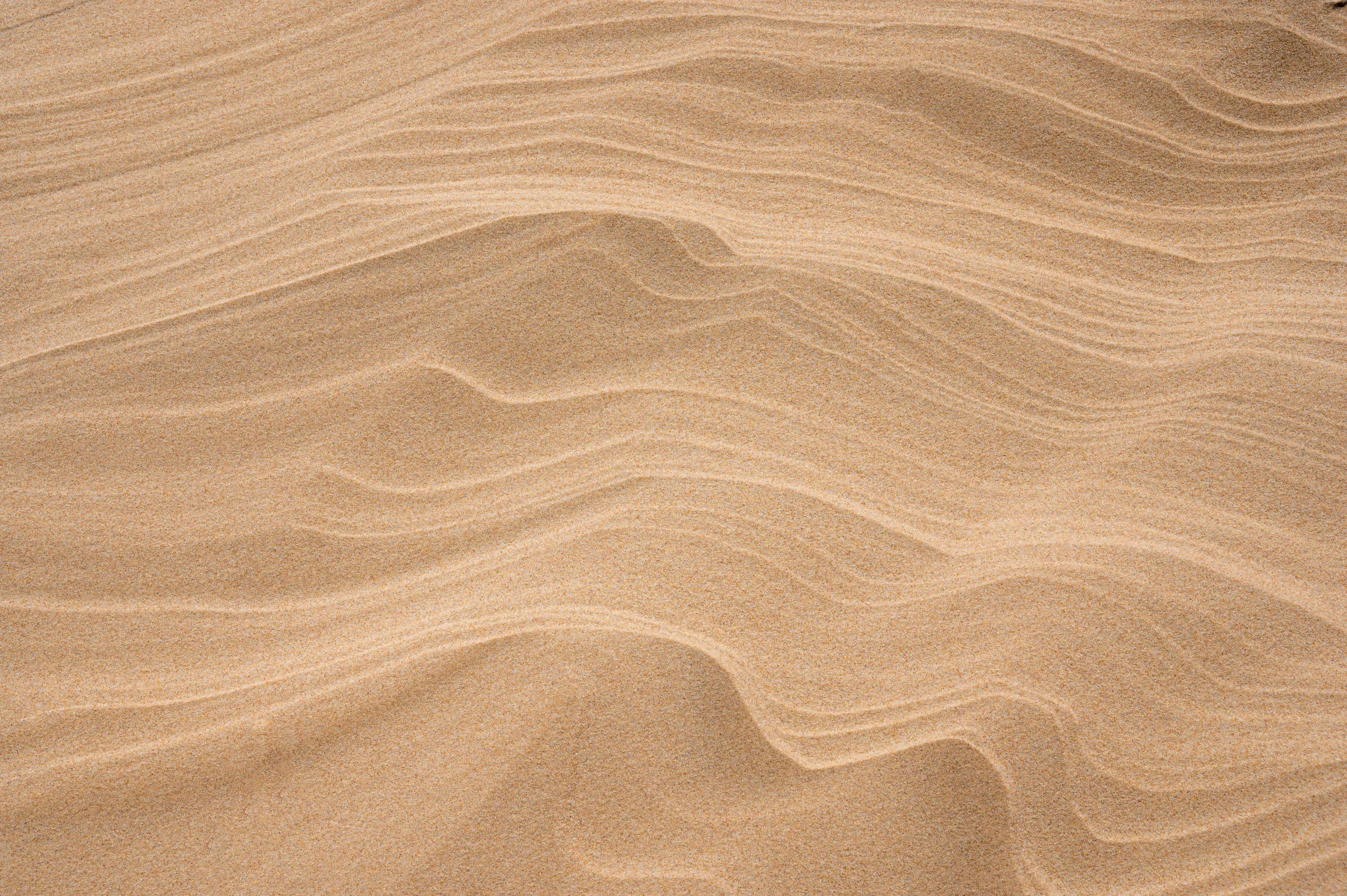 Close-up of sand dunes with ripples and ridges in a desert.