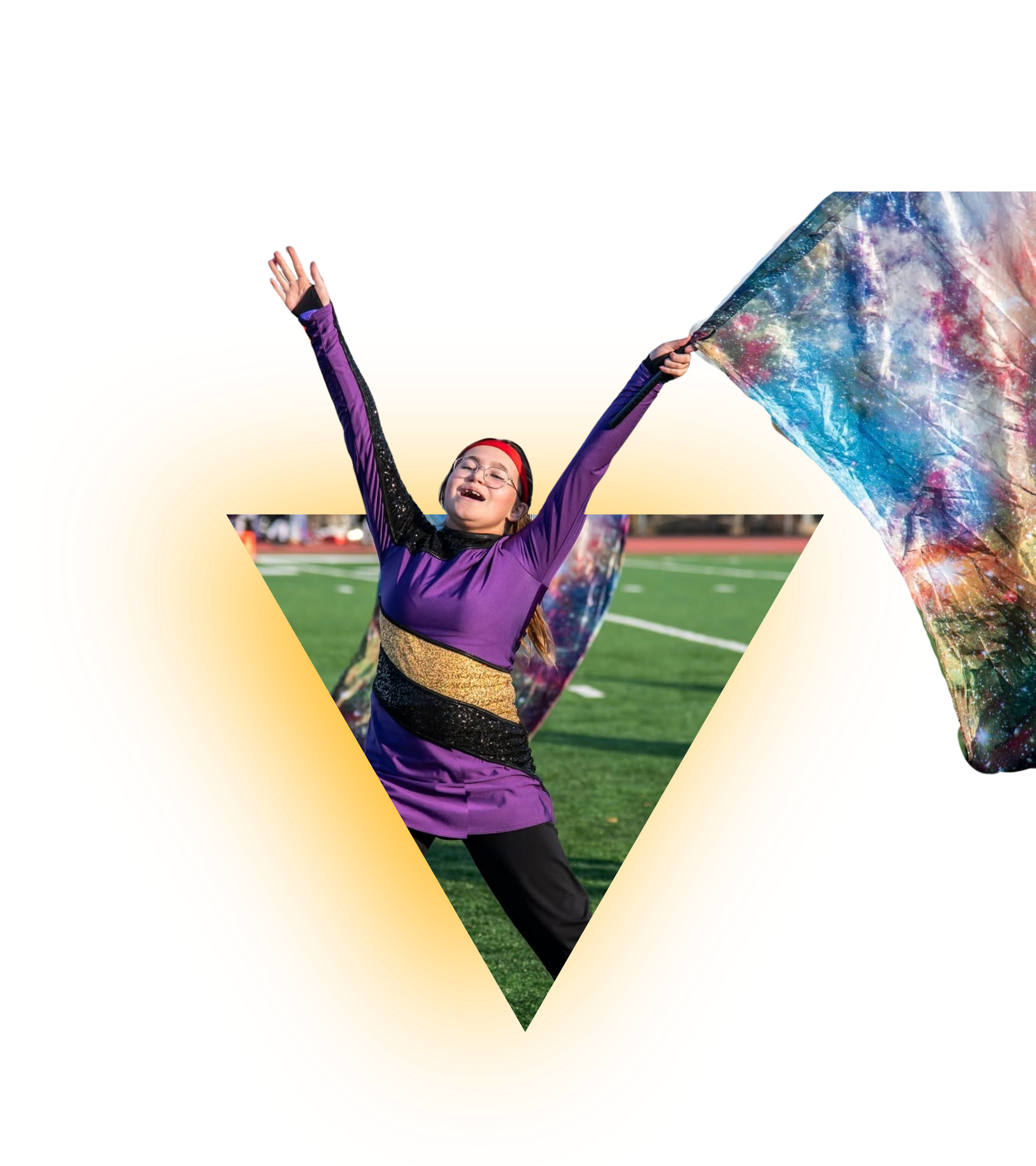 A young girl in glasses, a purple costume, and a red headband, joyfully holding a colorful galaxy-patterned flag while standing on a grassy sports field.