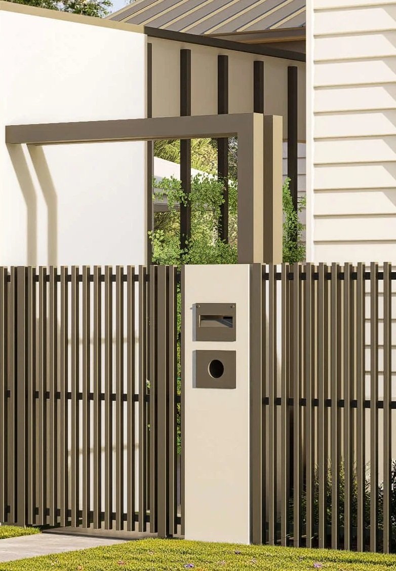 Modern residential gate with vertical wooden slats, mail slot, and circular doorbell, surrounded by a fence and greenery.
