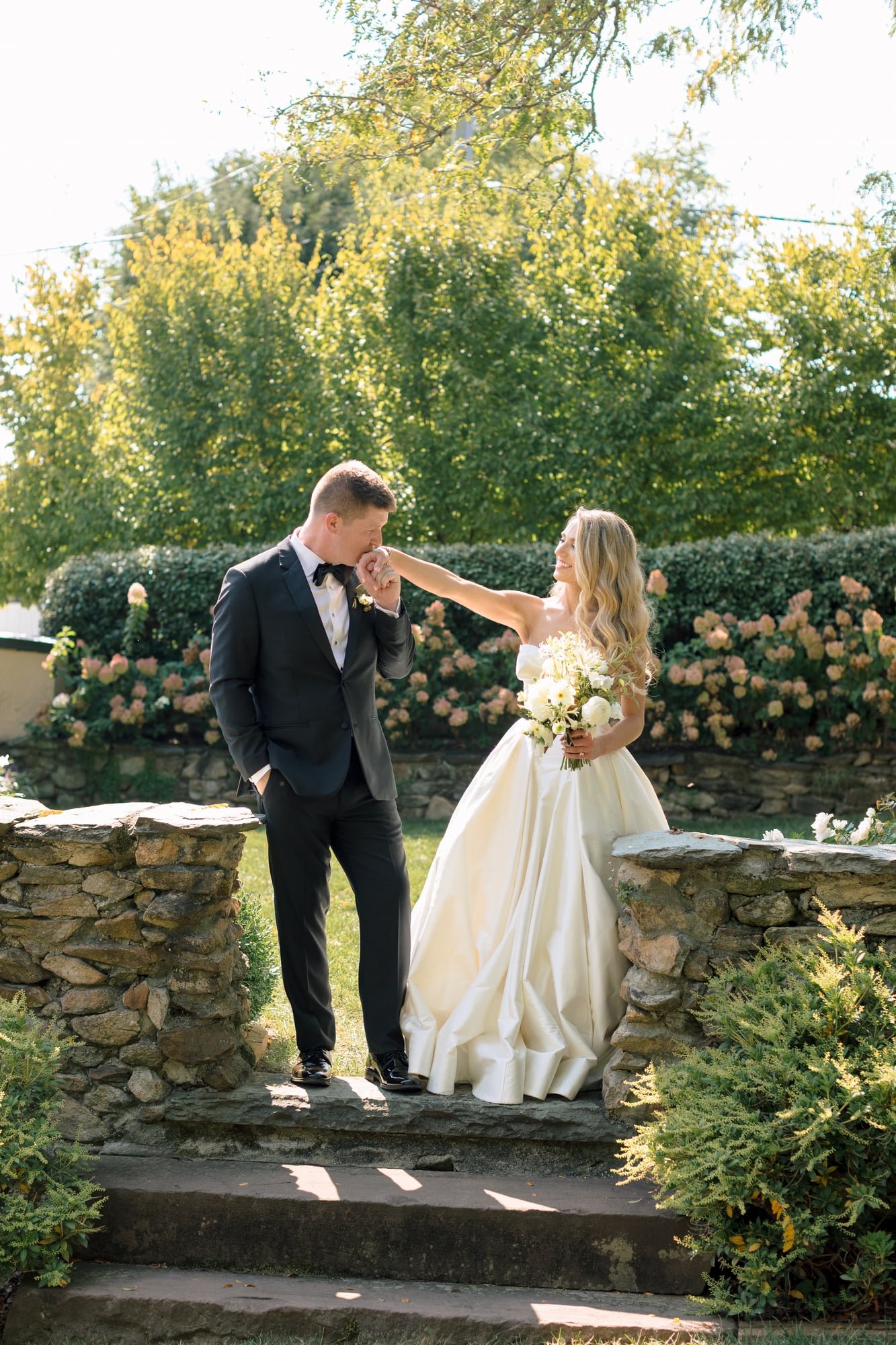 groom-kisses-bride-hand-garden-portrait-large.jpg