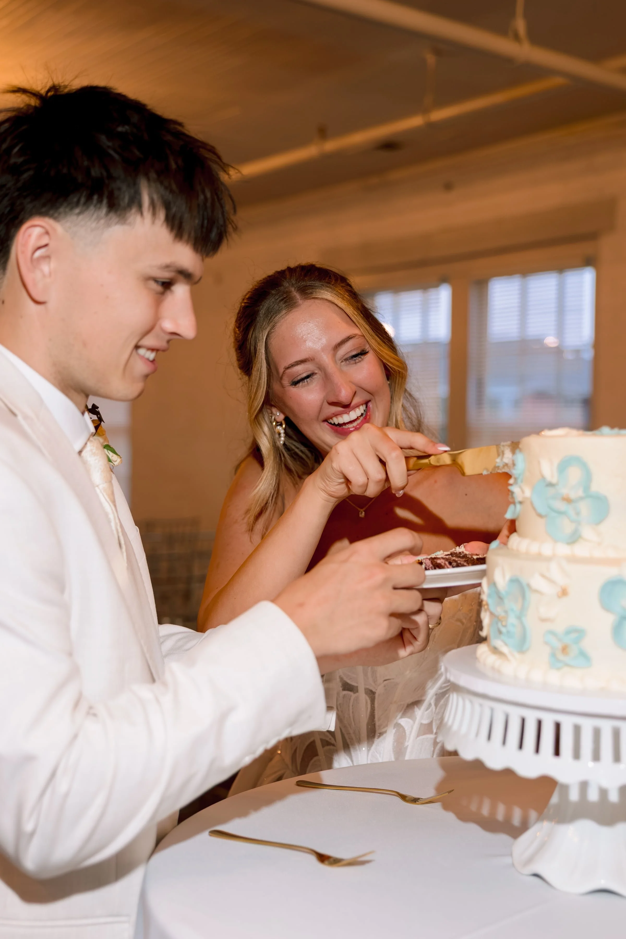 A bride and groom cutting their wedding cake together at their wedding reception.