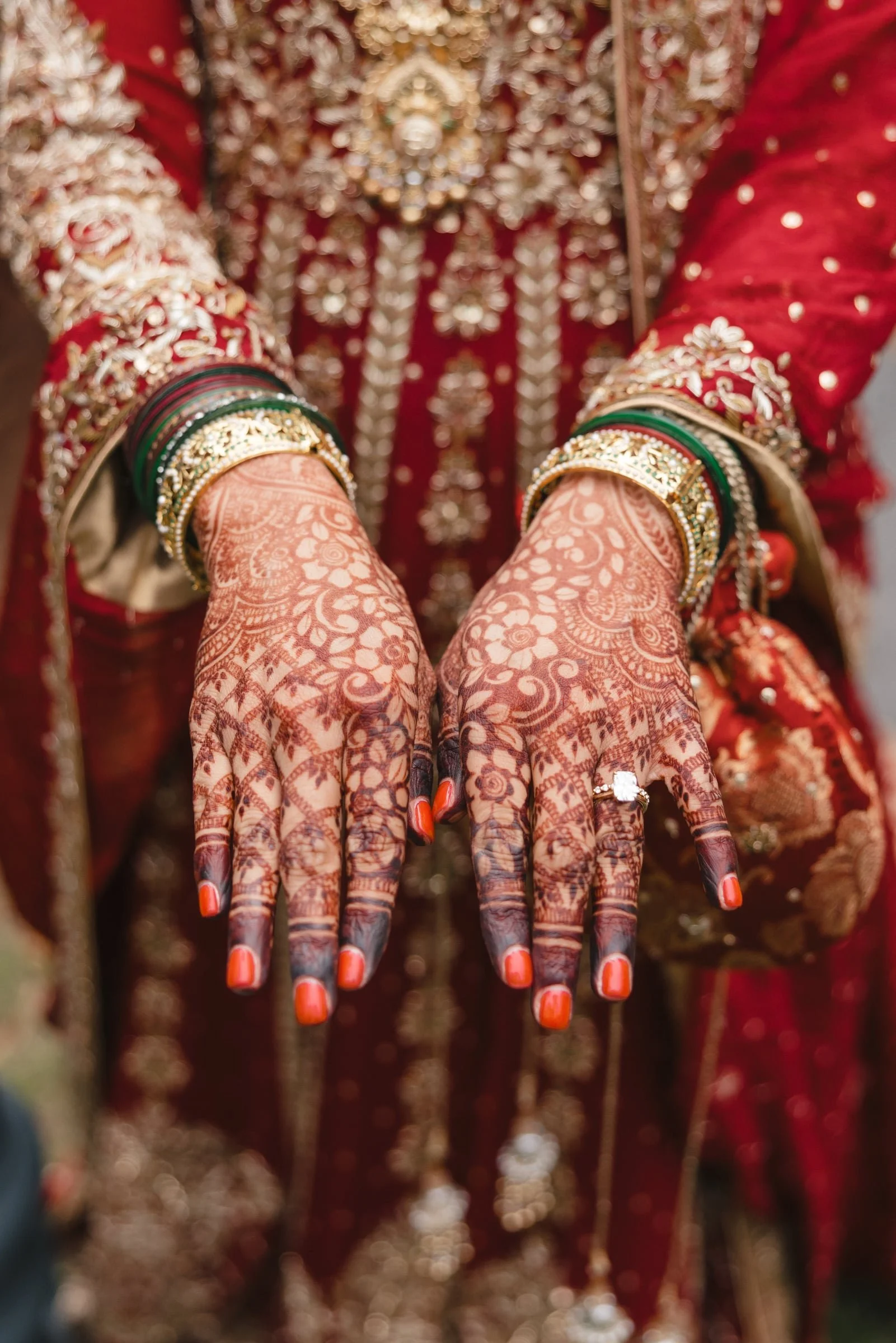 Indian wedding jewelry including bangles, mehndi (henna) on hands, and traditional red embroidered clothing.