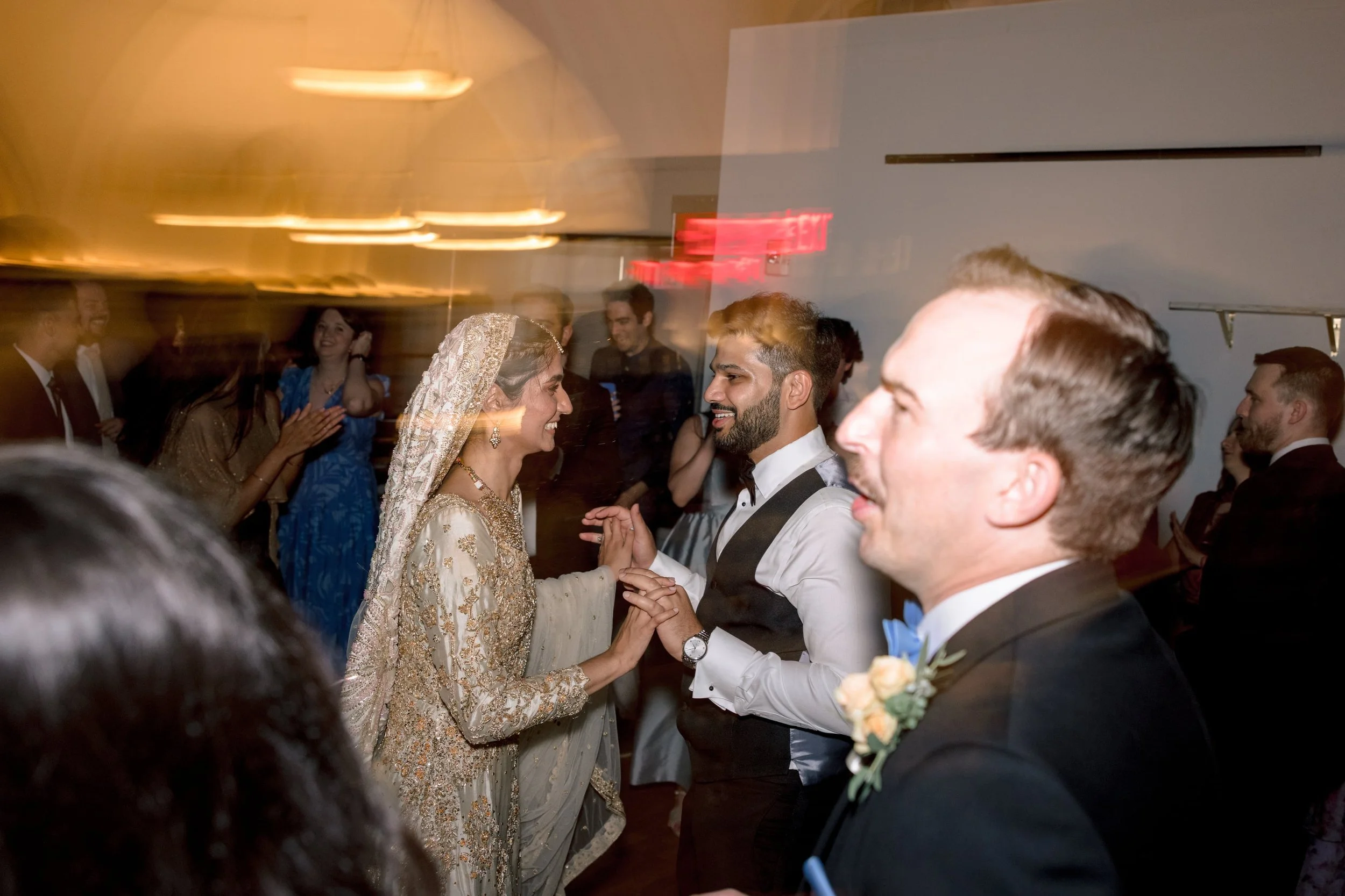 A bride and groom dancing together at a wedding reception, surrounded by guests in formal attire.