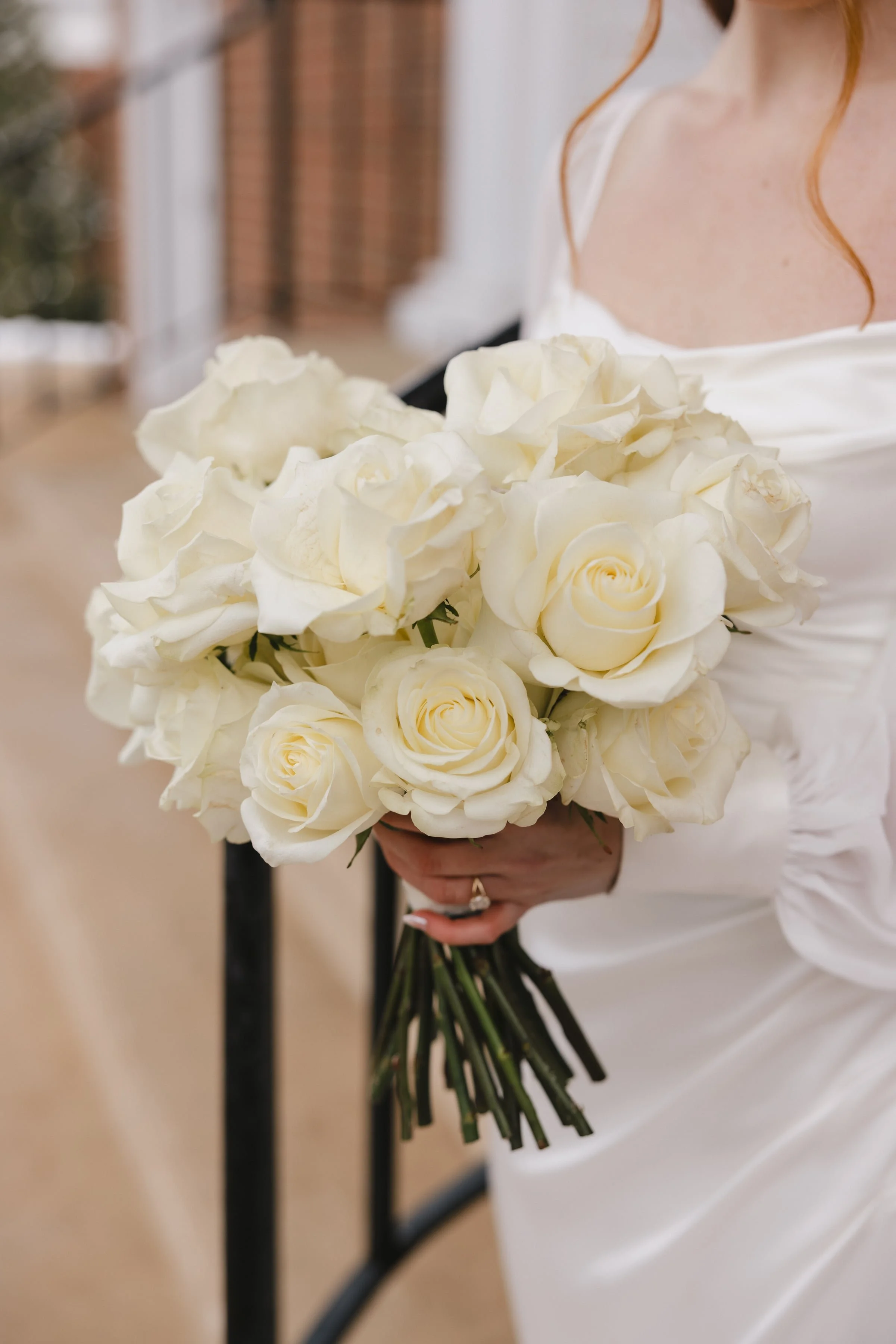 A woman in a white dress holding a large bouquet of white roses.