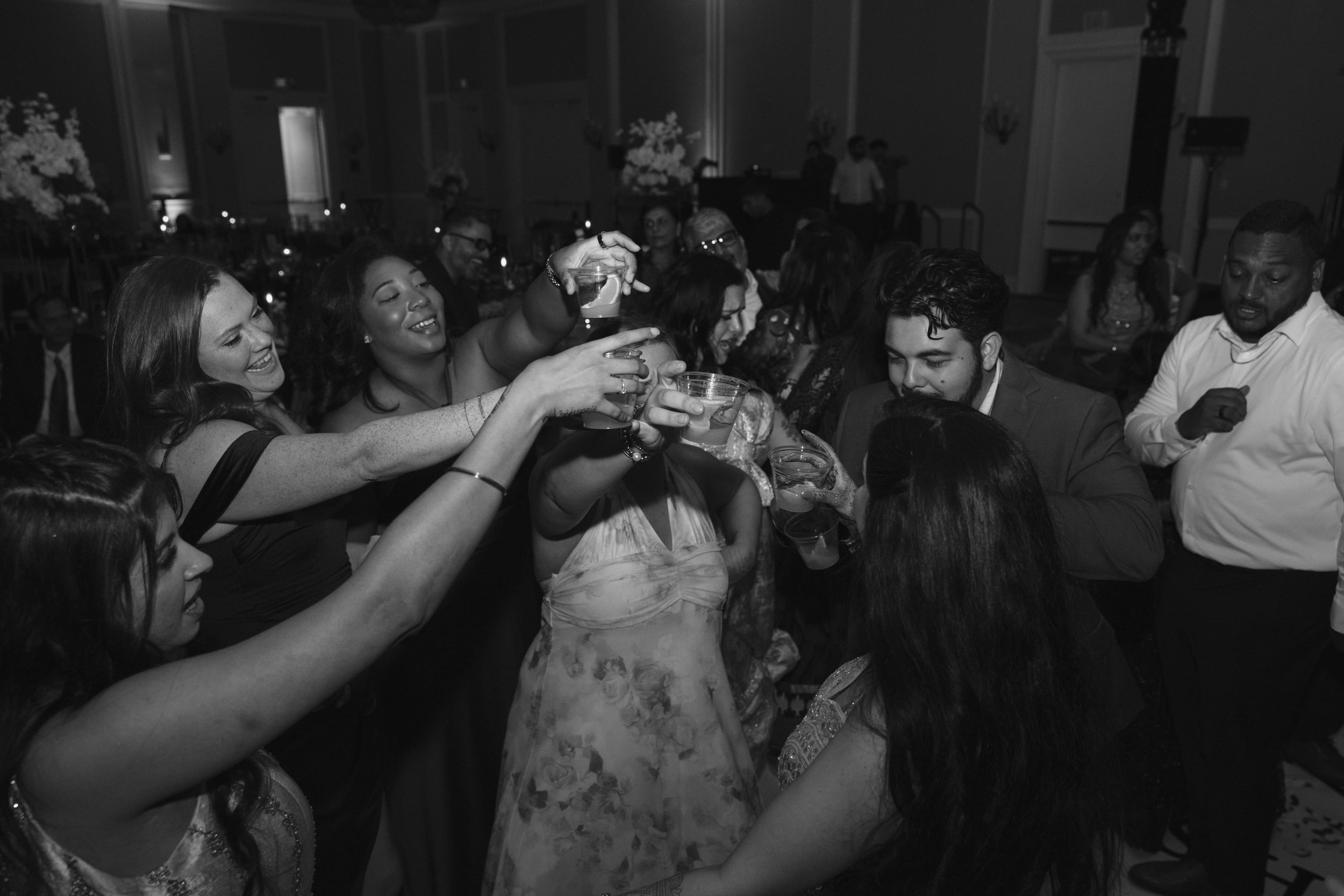 Group of people at a celebration or party, raising glasses for a toast in a formal indoor setting.