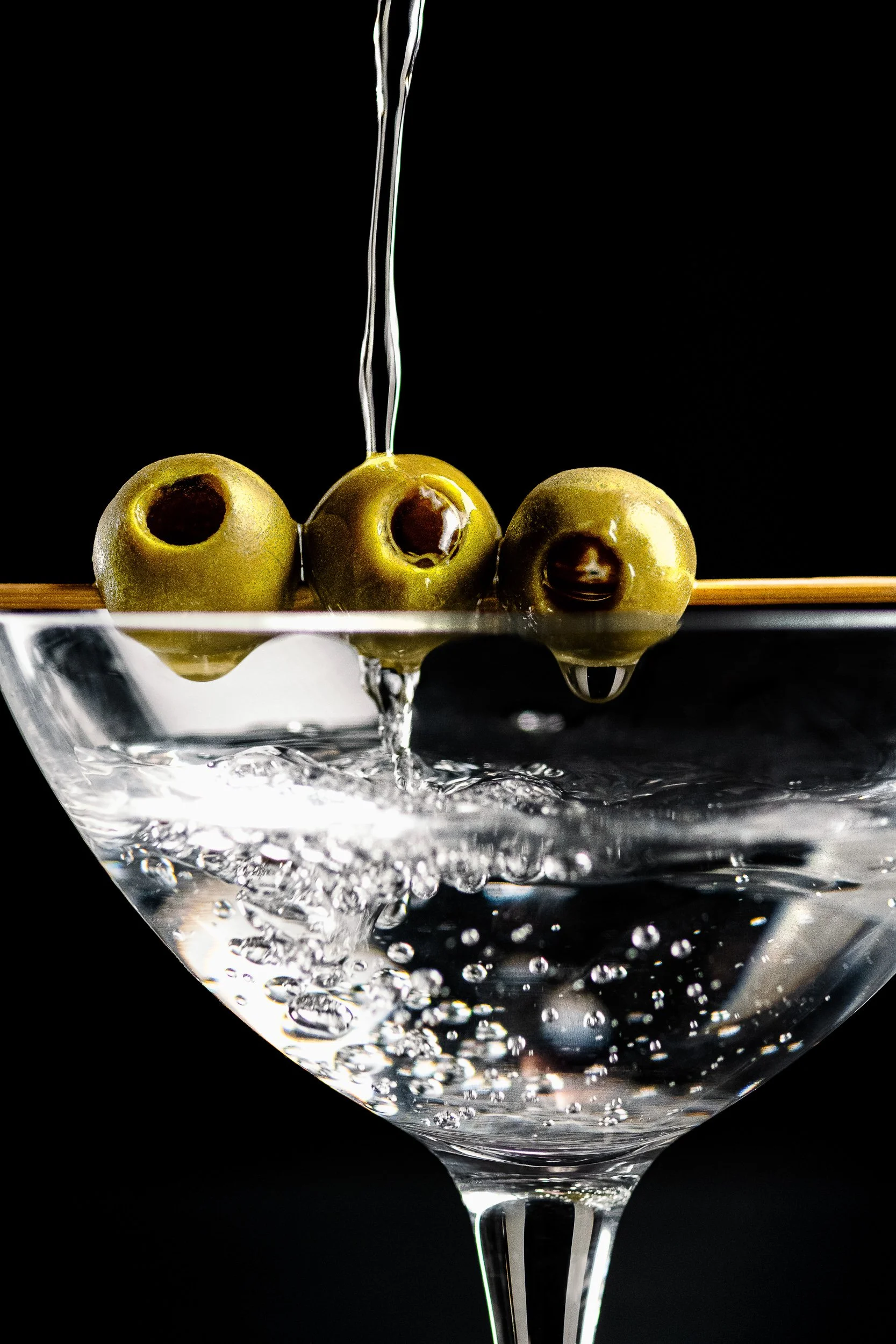 Commercial beverage photography featuring a martini cocktail with green olives and a dynamic pouring shot, created for advertising, bar and drinks campaigns