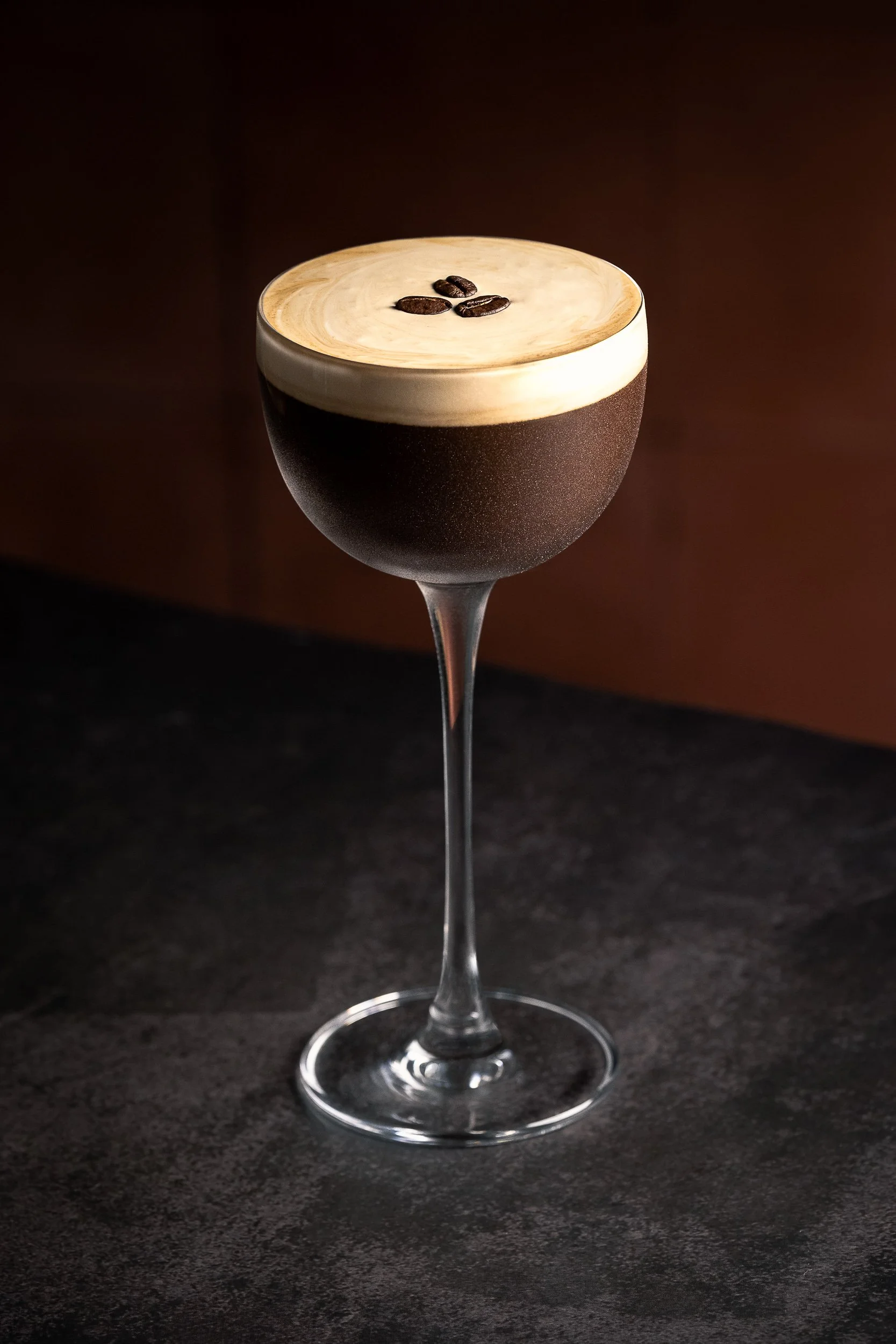 Commercial cocktail photography of an espresso martini with creamy foam and coffee beans, styled for beverage brands, bars and advertising campaigns