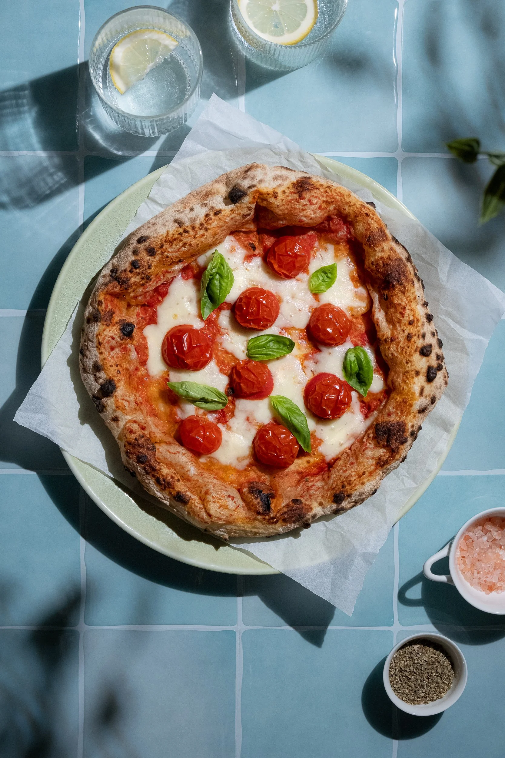 Professional food styling and editorial food photography of Margherita pizza with mozzarella, roasted cherry tomatoes and fresh basil, created for restaurant, food brand and advertising content