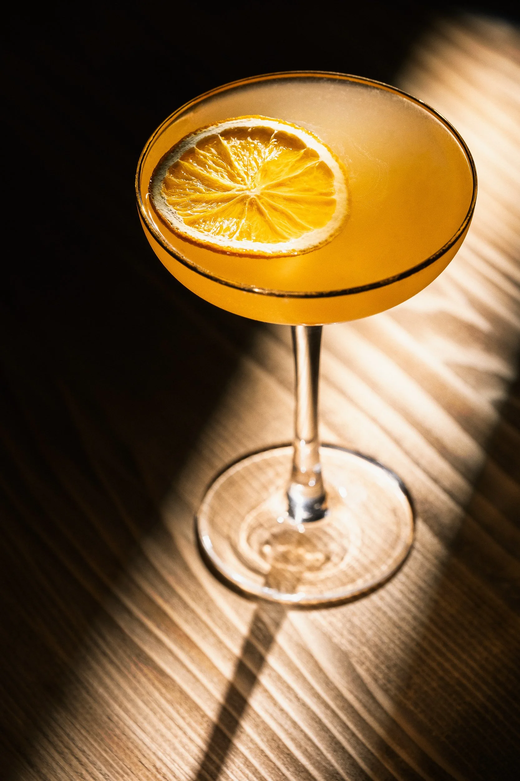 Commercial beverage photography of an orange citrus cocktail with dried lemon garnish, styled and photographed for drinks brands, bars and advertising campaigns