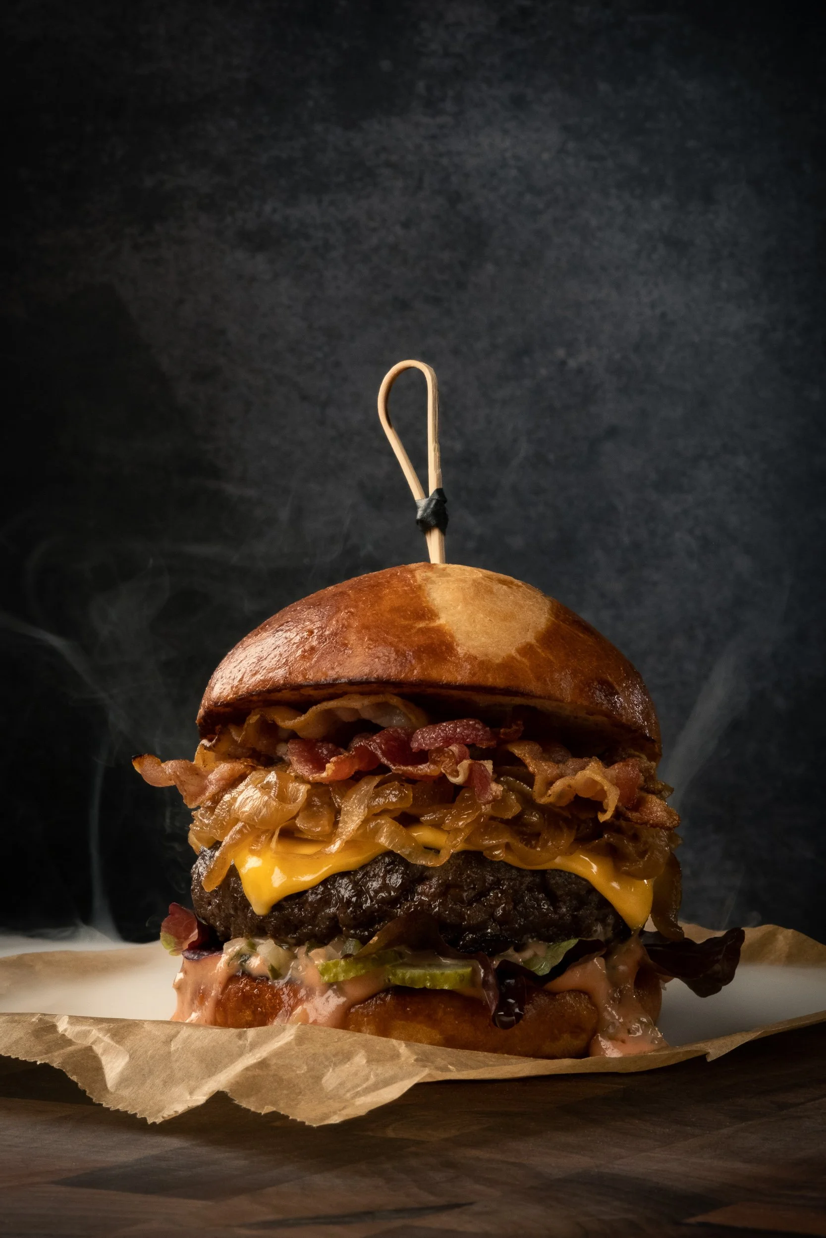 Commercial food photography and food styling of a gourmet burger with bacon, melted cheese and caramelized onions, created for restaurant and advertising content