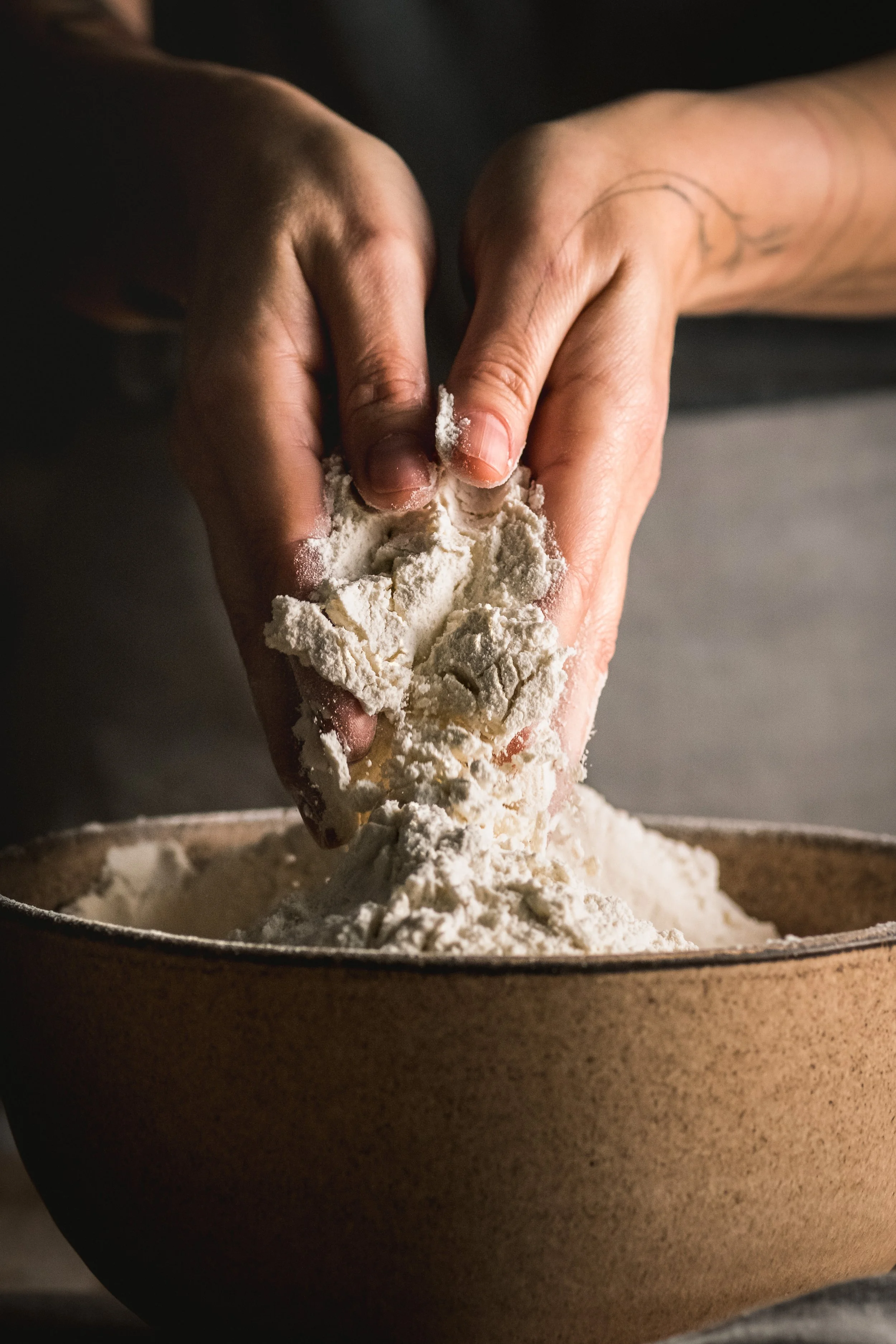 Hands mixing flour in a bowl, suggesting baking or cooking process.