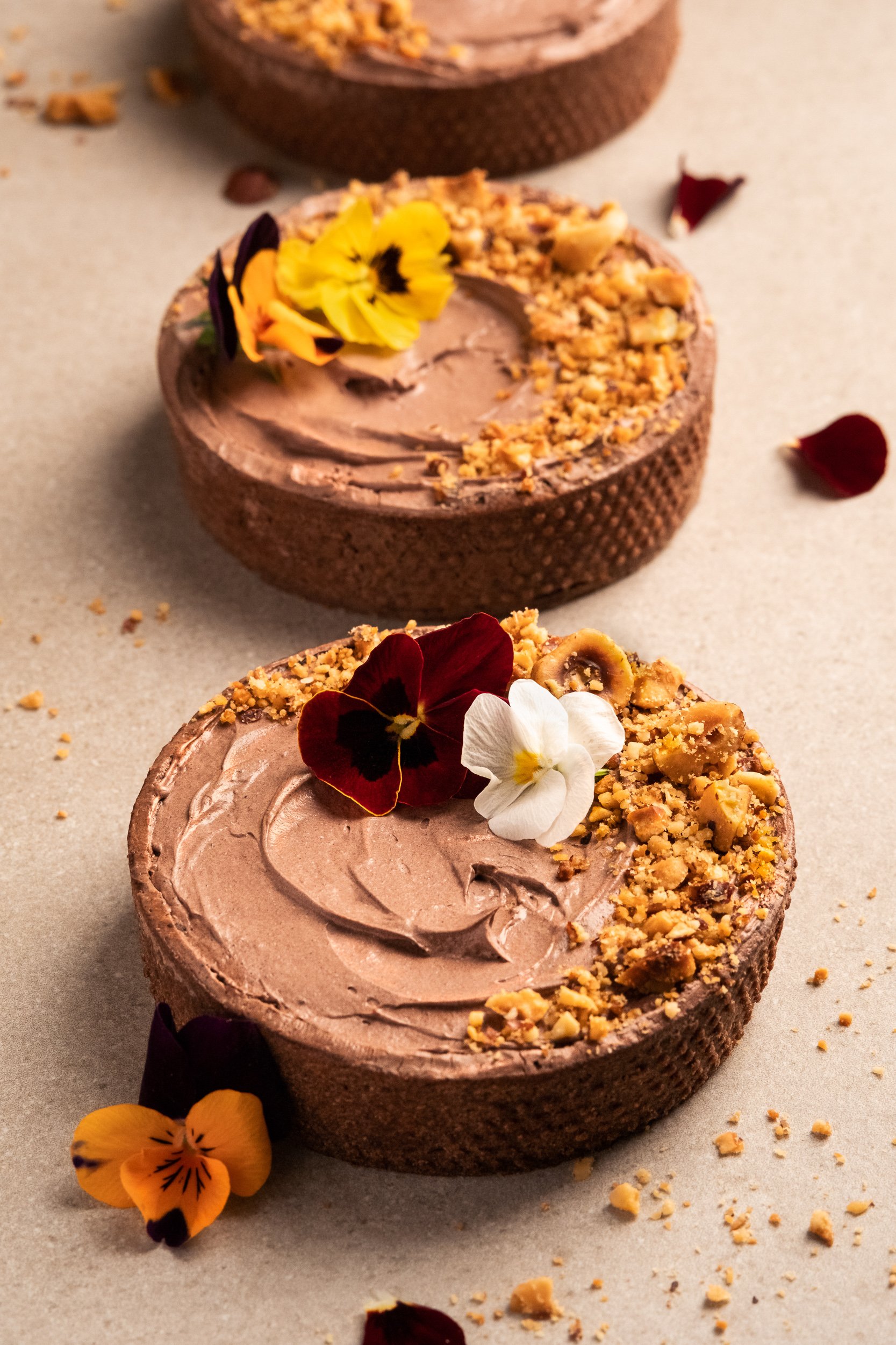 professional food photo of a chocolate tart with nuts and flowers. 