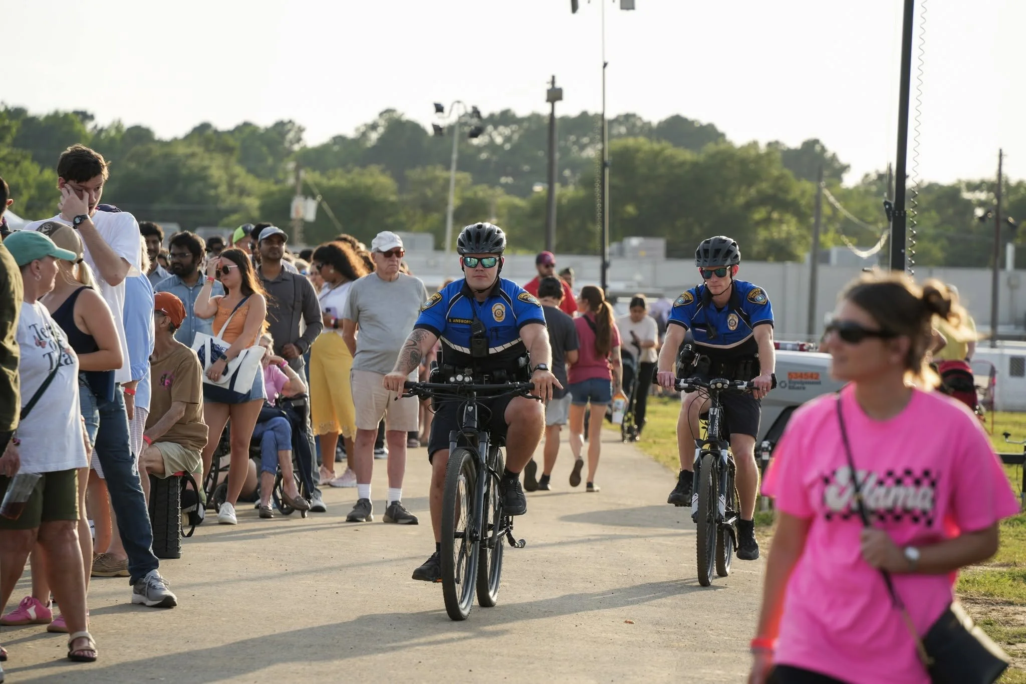 Crowd of people walking and cycling outdoors during daytime, with police officers in the foreground.