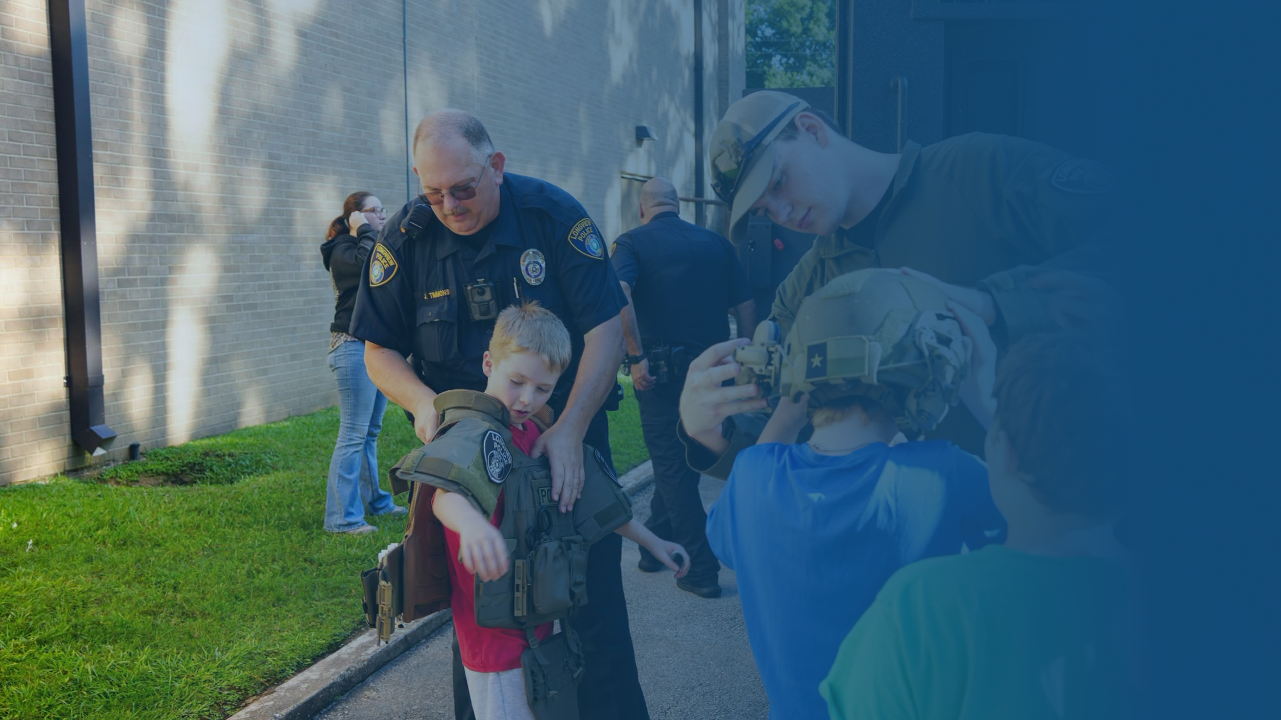 Police officers and a young boy with a backpack interacting outside near a brick building.