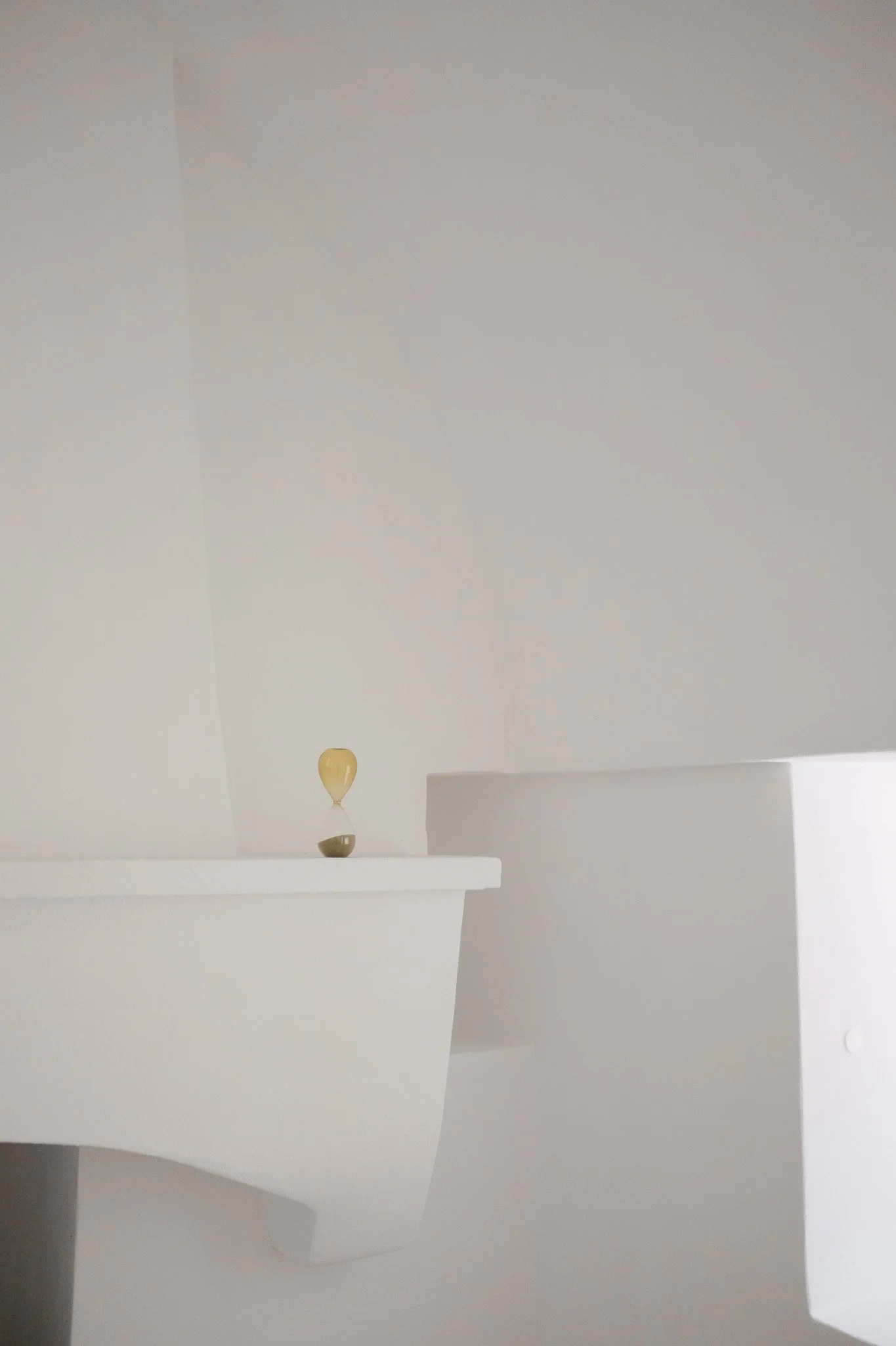 A white interior space with floating shelves and a pendant light fixture.