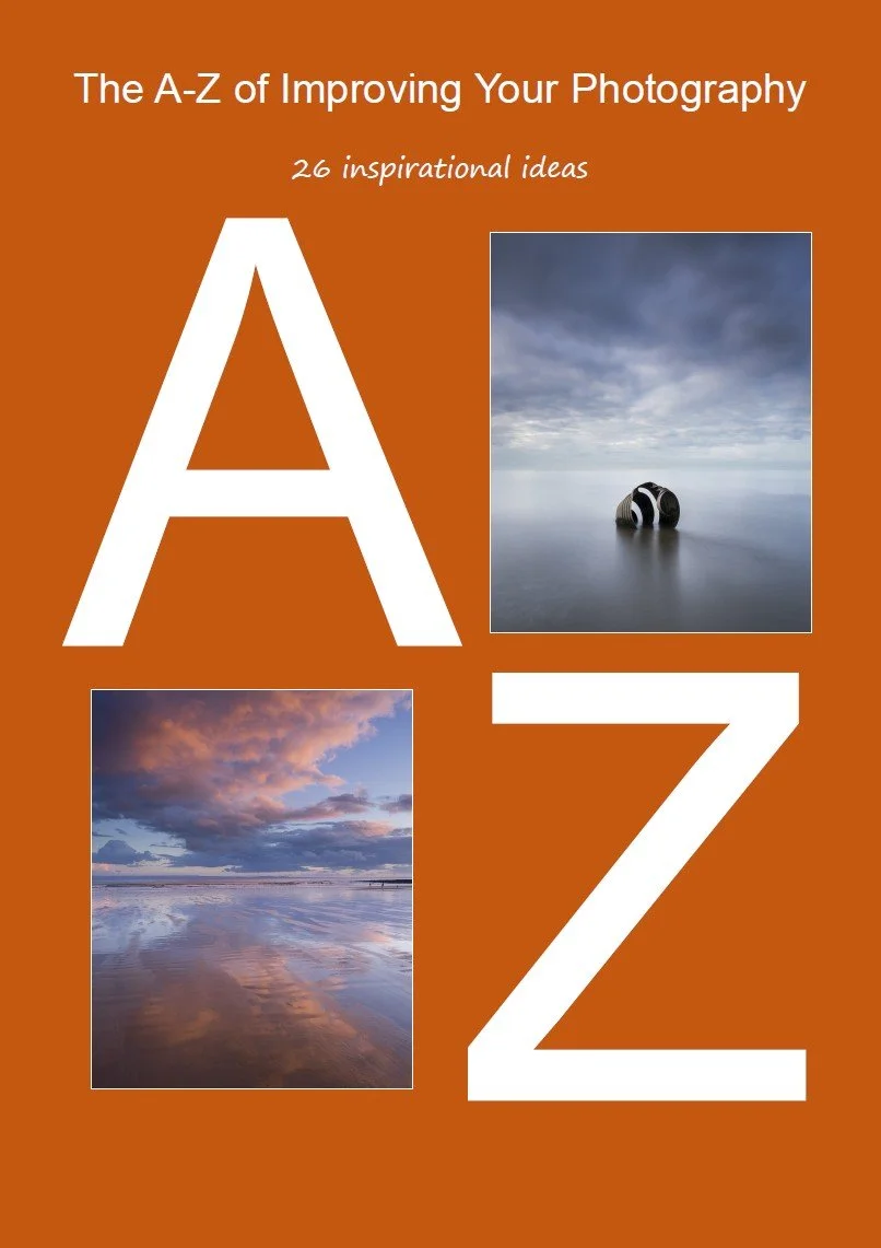 Cover page of a photography guide titled 'The A-Z of Improving Your Photography' with a subtitle '26 inspirational ideas' and includes two landscape photographs: one of a cloudy sky reflecting over water with a distant horizon, and another of a serene sky reflected on the wet sand of a beach shore.