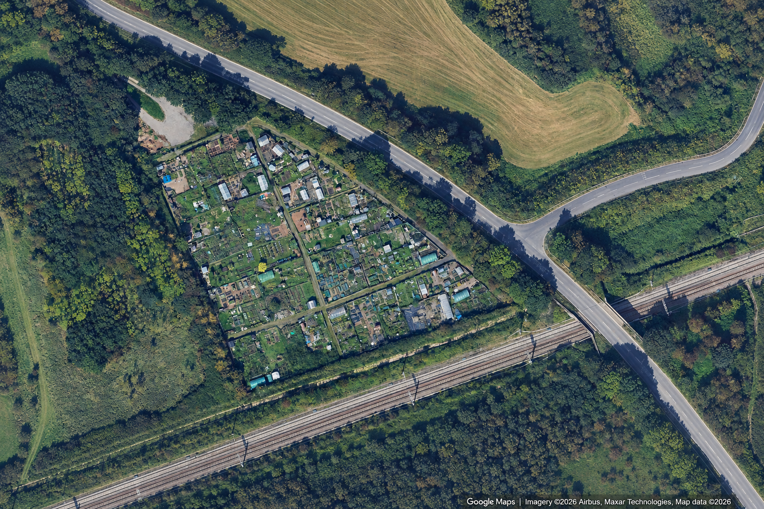 An aerial view of a My Patch Swindon garden plots, surrounded by trees, roads, and train tracks.