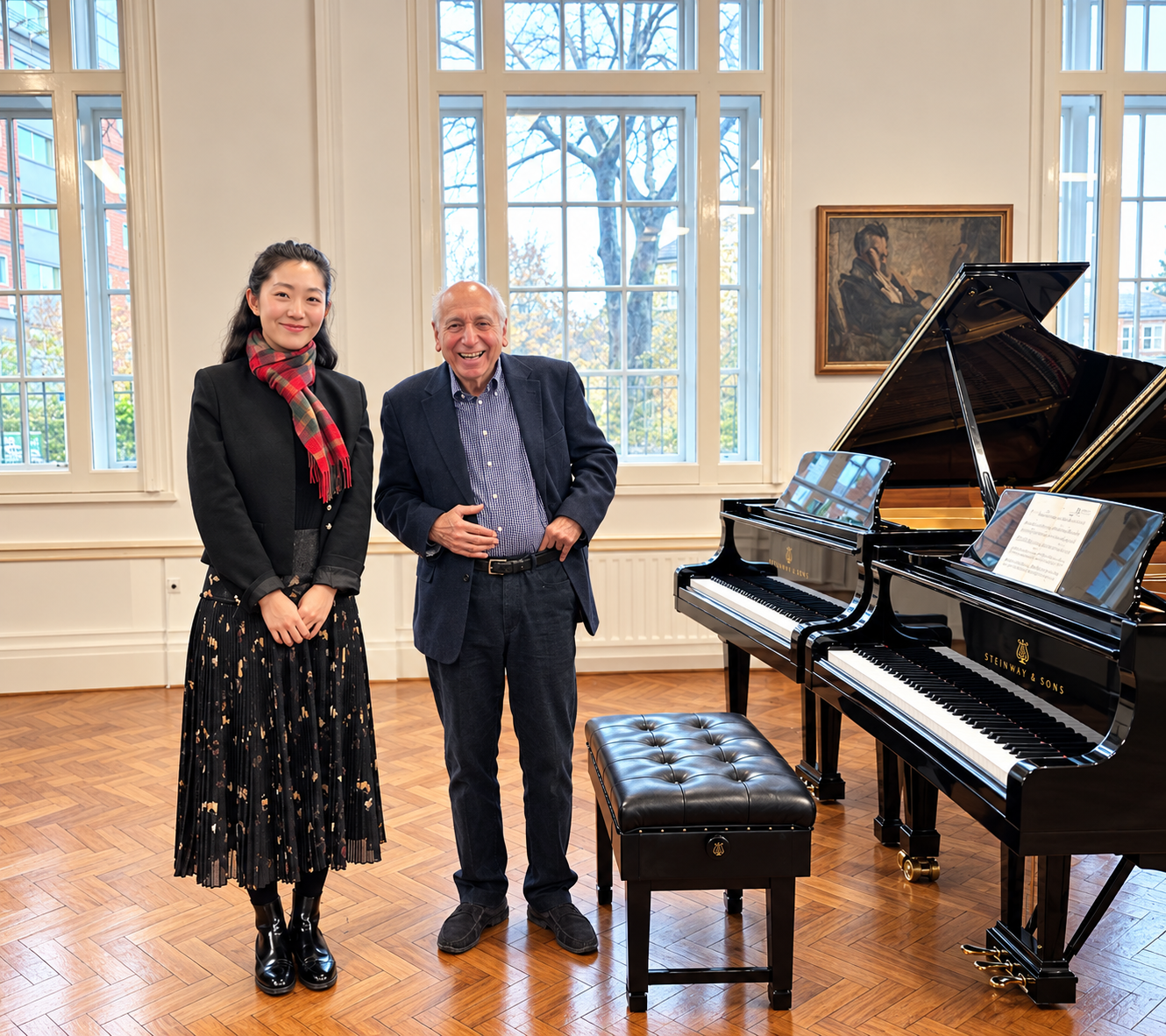 Two musicians pose beside two Steinway & Sons grand pianos in a bright music room.