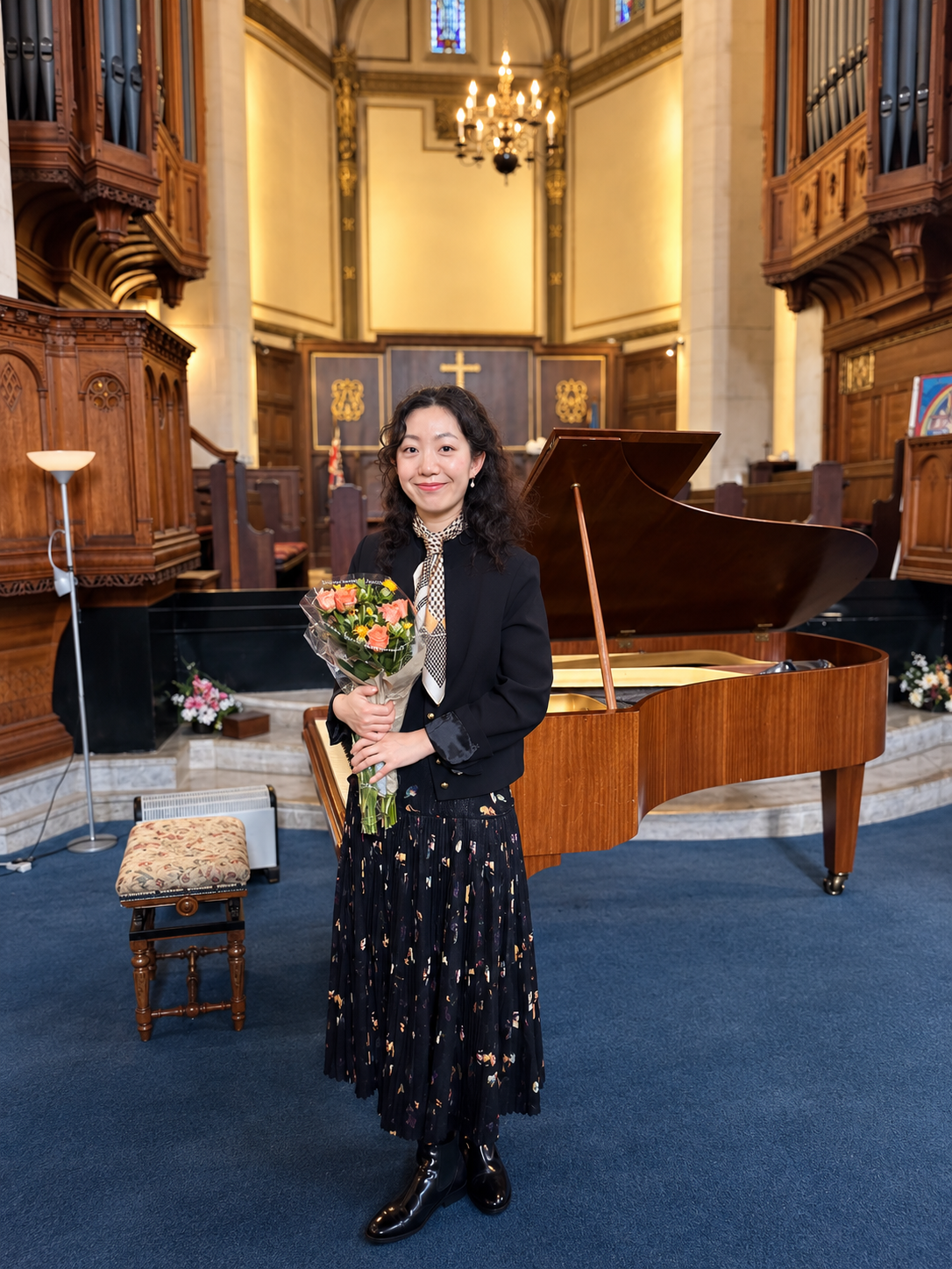 Woman holding a bouquet beside a grand piano inside a church with ornate pipe organs