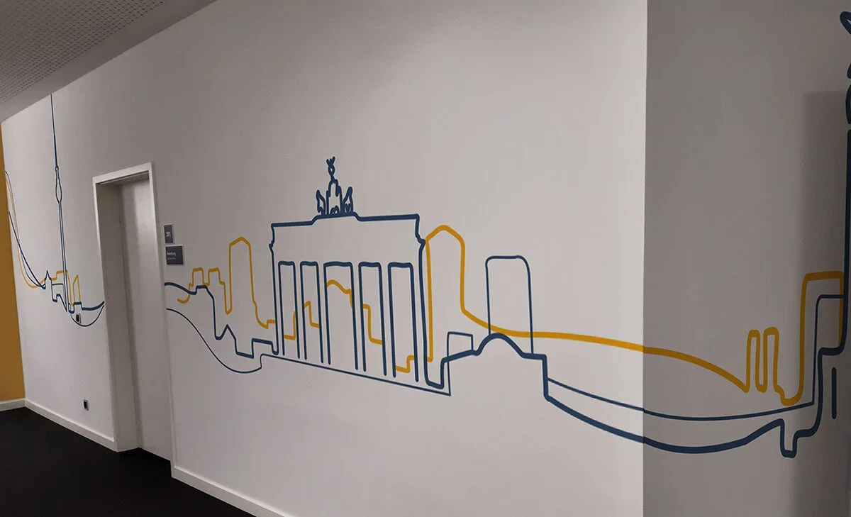 Line art mural of city skyline on a white wall, featuring landmarks and buildings in blue and yellow lines.