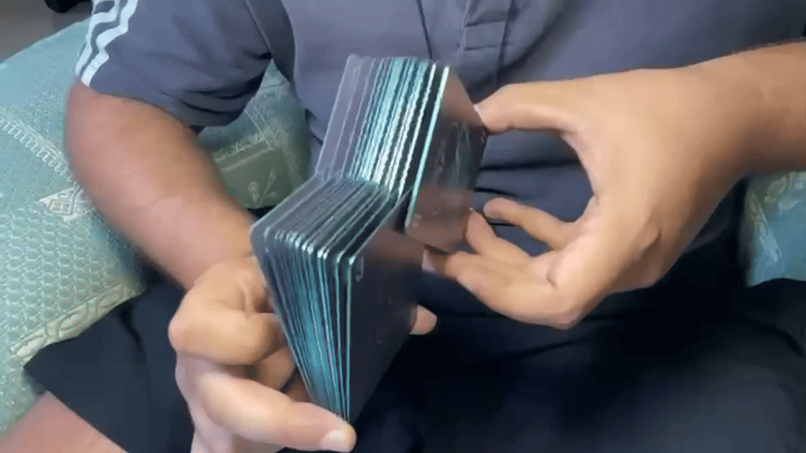 Two people passing a stack of playing cards between their hands.