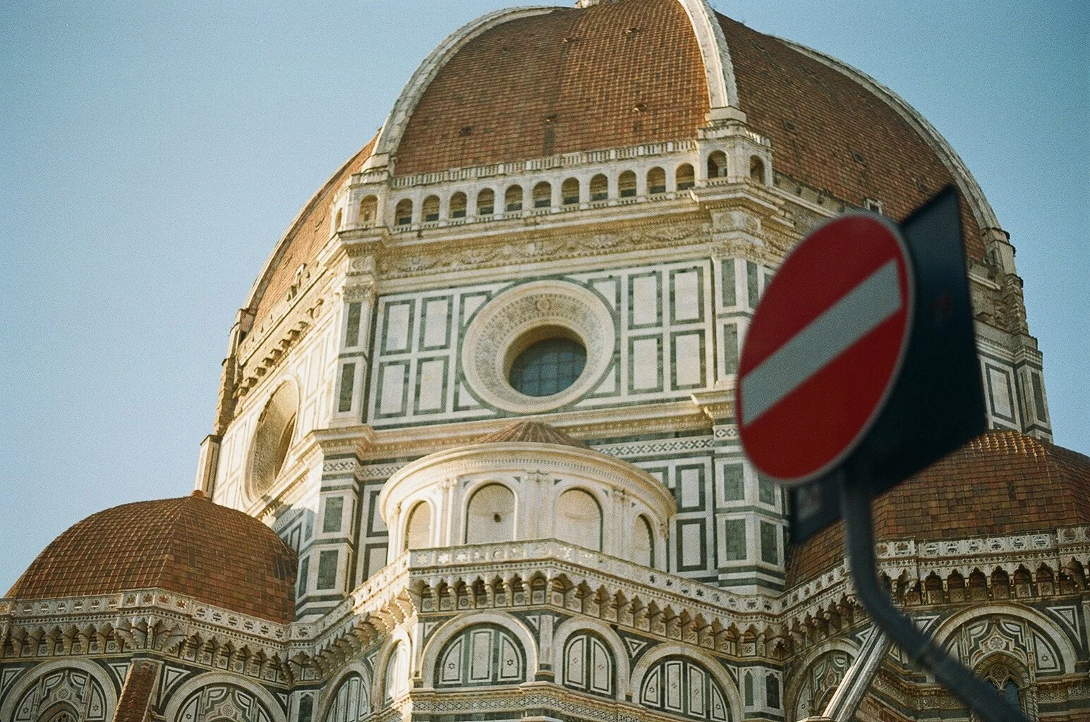 Close-up of the Florence Cathedral (Cattedale di Santa Maria del Fiore) with a no-entry traffic sign in the foreground. Photo by Taha Solakoglu.