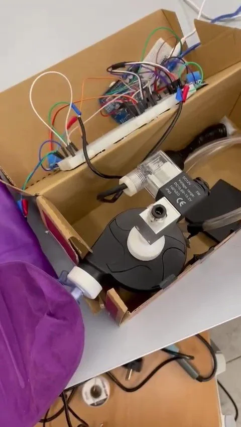 Electrical components, wires, and a motor are placed inside a cardboard box, Part of a working prototype in an industrial design class.