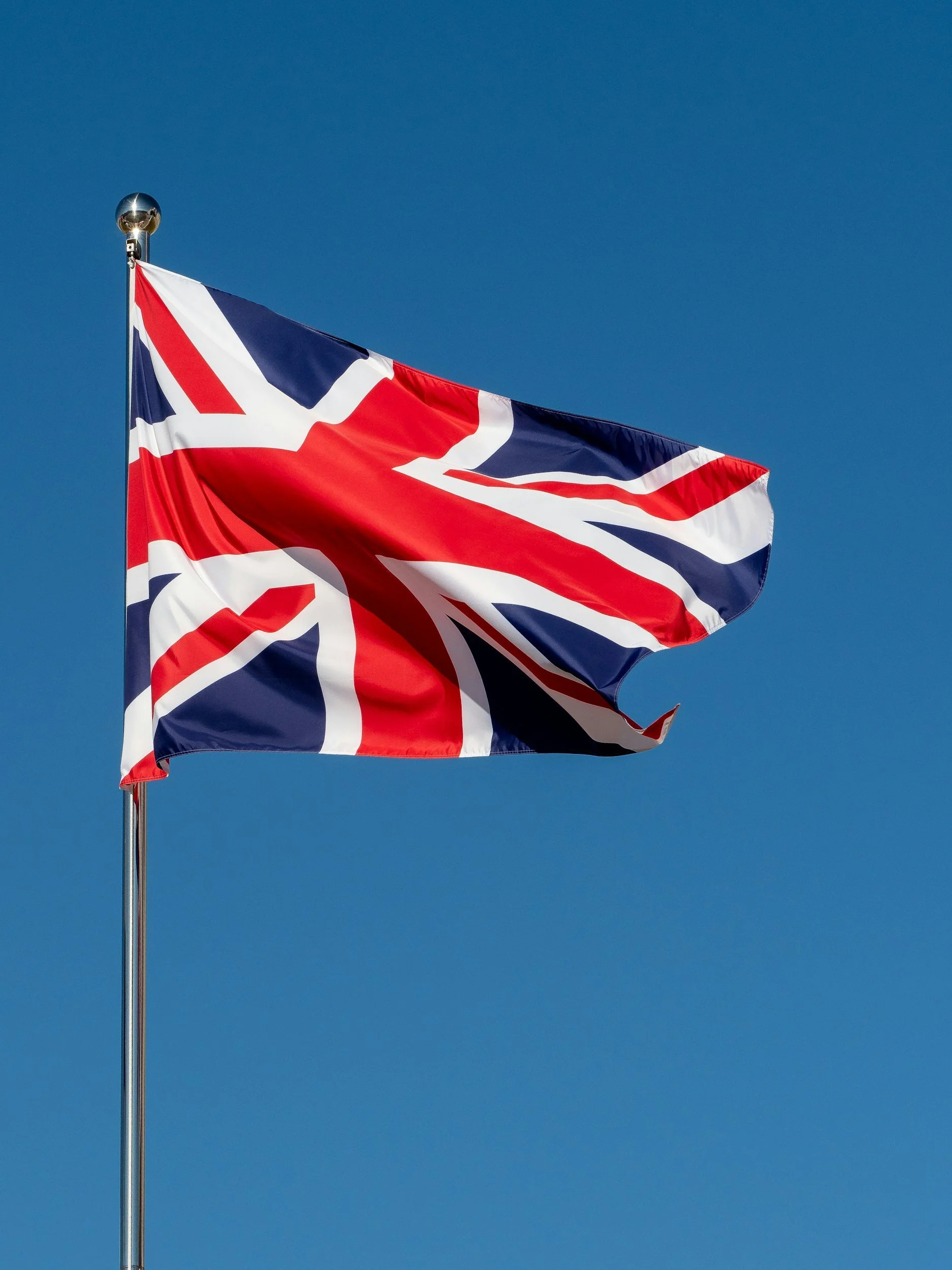 A Union Jack flag flying against a clear blue sky.