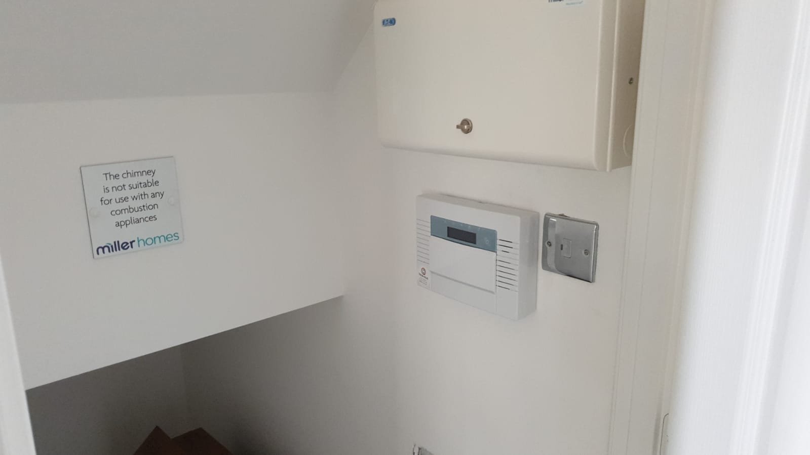 Interior wall with a warning sign about chimneys, a thermal sensor, an electrical outlet, and a distribution box.