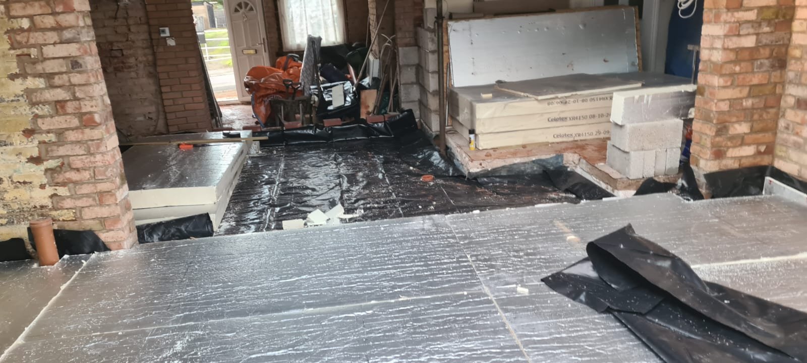 Indoor construction site with brick columns and flooring materials, construction tools, and partially built surfaces