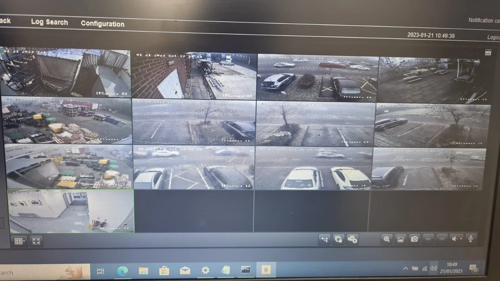 Security camera monitor displaying multiple surveillance footage views of parking lots and exterior areas of a building from different angles.
