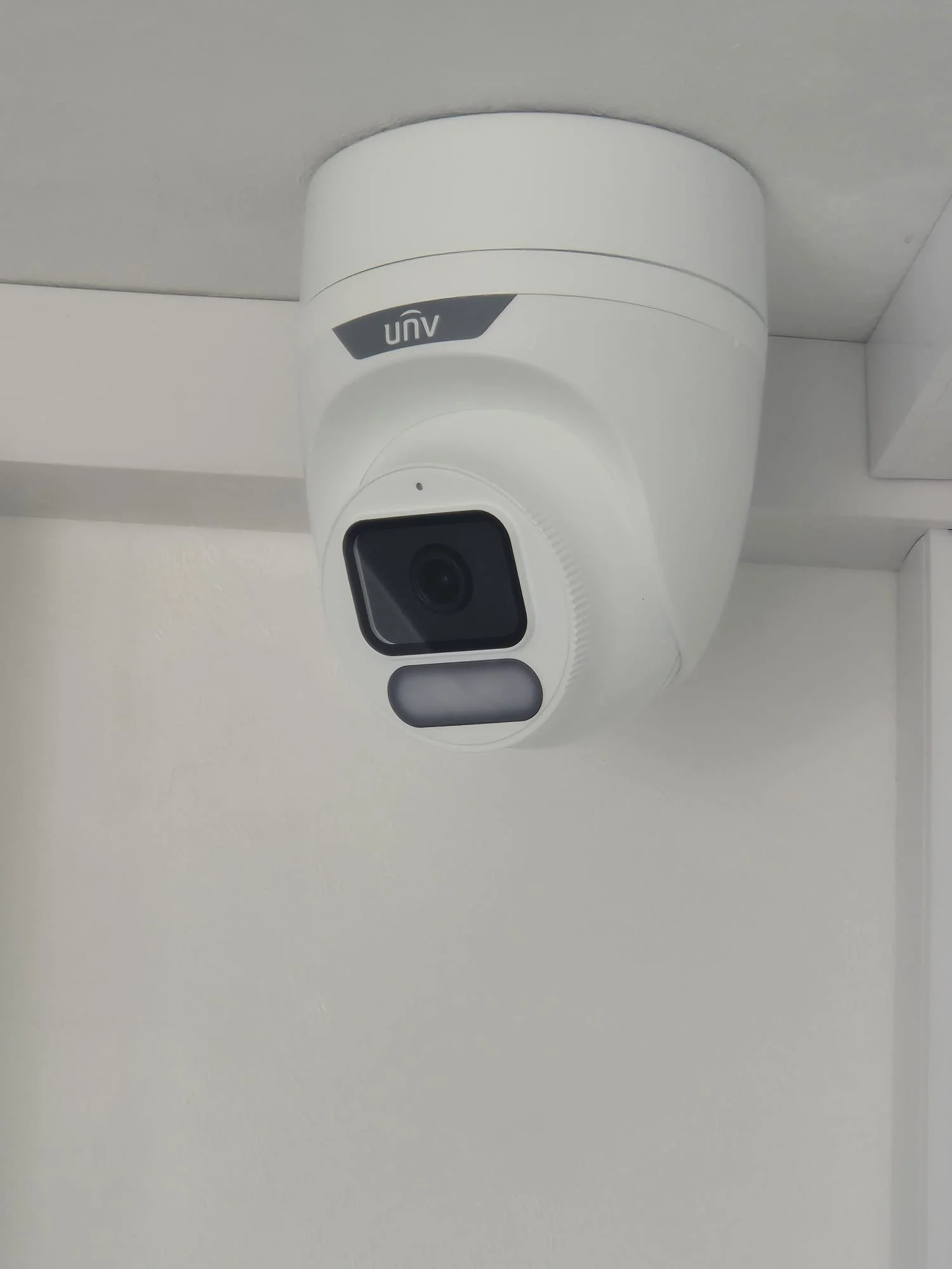 A white security camera mounted on the ceiling with the brand name 'UNV' visible.