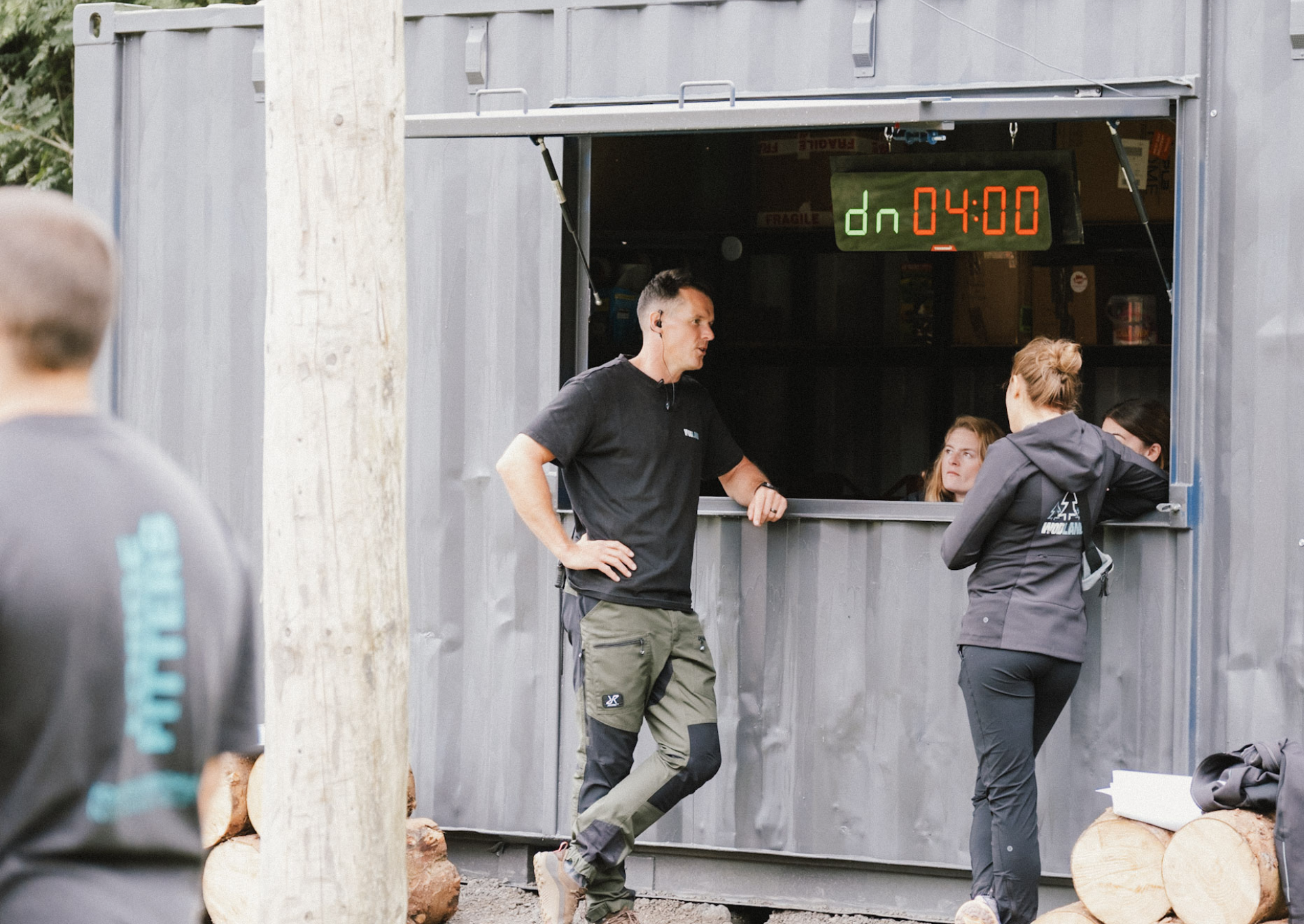 People gathered around a window with a digital countdown clock showing 4 minutes left, outside a building, possibly at an event or race.