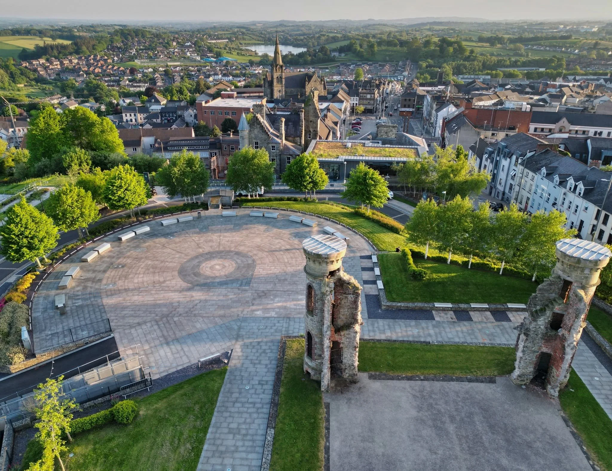 Aerial view of a historic town with a large church, surrounding buildings, trees, and distant countryside.