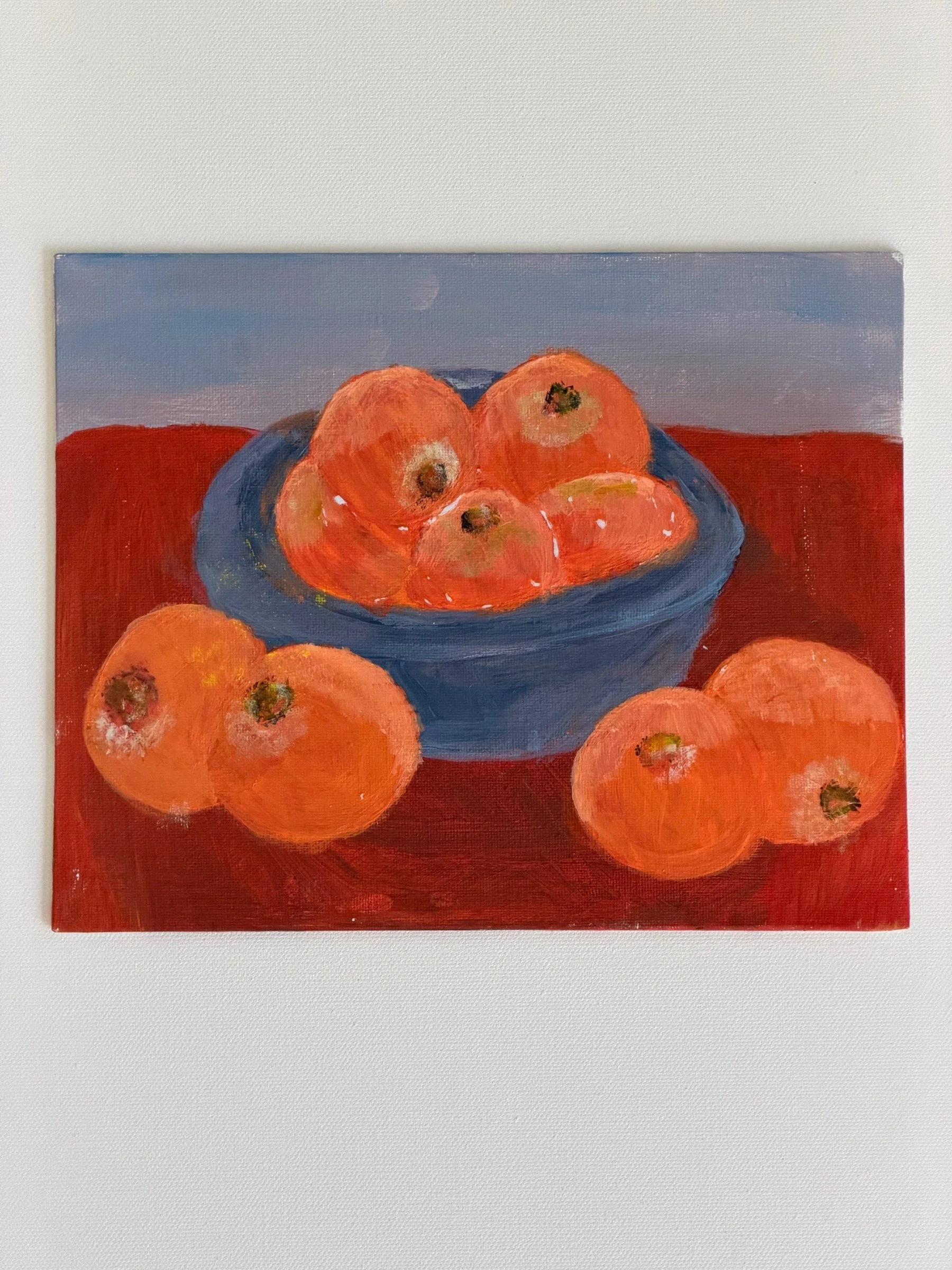 STRUCTURAL FRUIT STUDY.  Acrylic on paper. 8×10". Oranges in a blue bowl on a deep red cloth, with three more resting in front of it. Built from blocks of complementary color — orange against blue on a warm red ground — so volume is described by colo