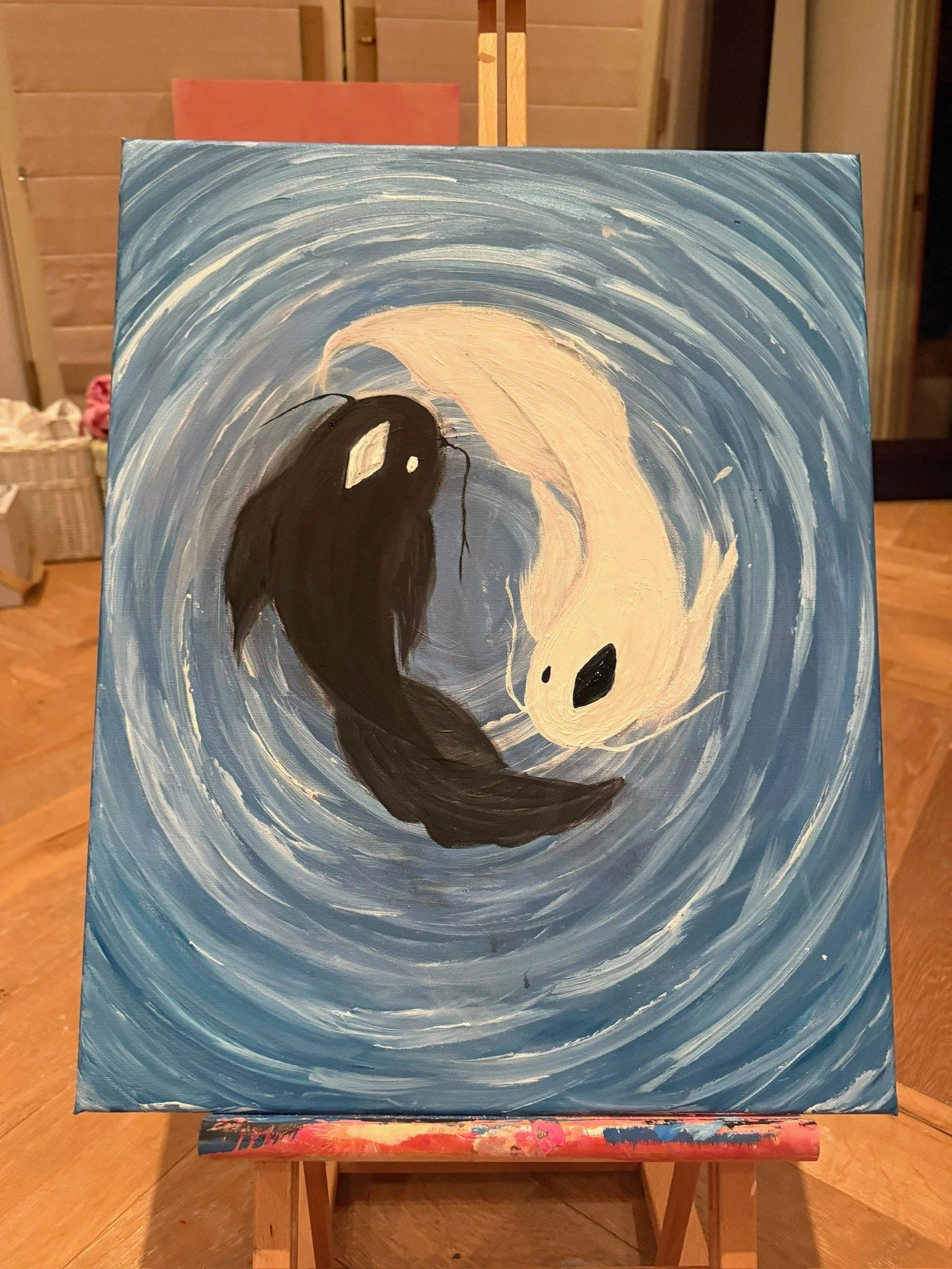 YIN YANG. Acrylic on canvas. 18×24". Two koi, one black and one white, curve around each other to form a yin-yang circle in swirling blue water. The brushwork spirals outward from the center, so the water carries the same circular motion as the fish.