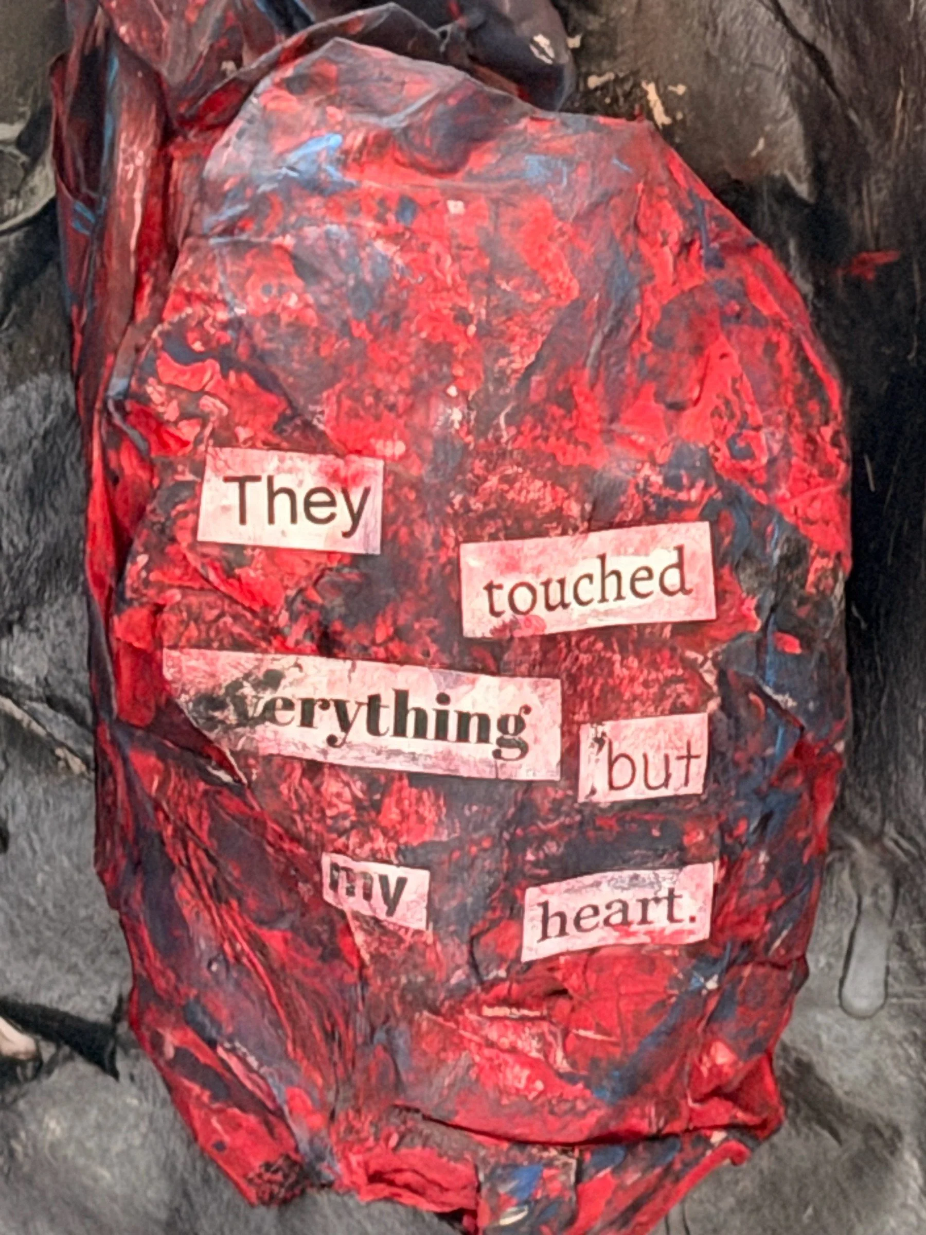UNTITLED (THEY TOUCHED EVERYTHING). Acrylic and collage, three-dimensional. A crumpled three-dimensional form painted in red and black, worked until the surface is heavily built up. Cut-out printed words are set across it, reading: They touched every