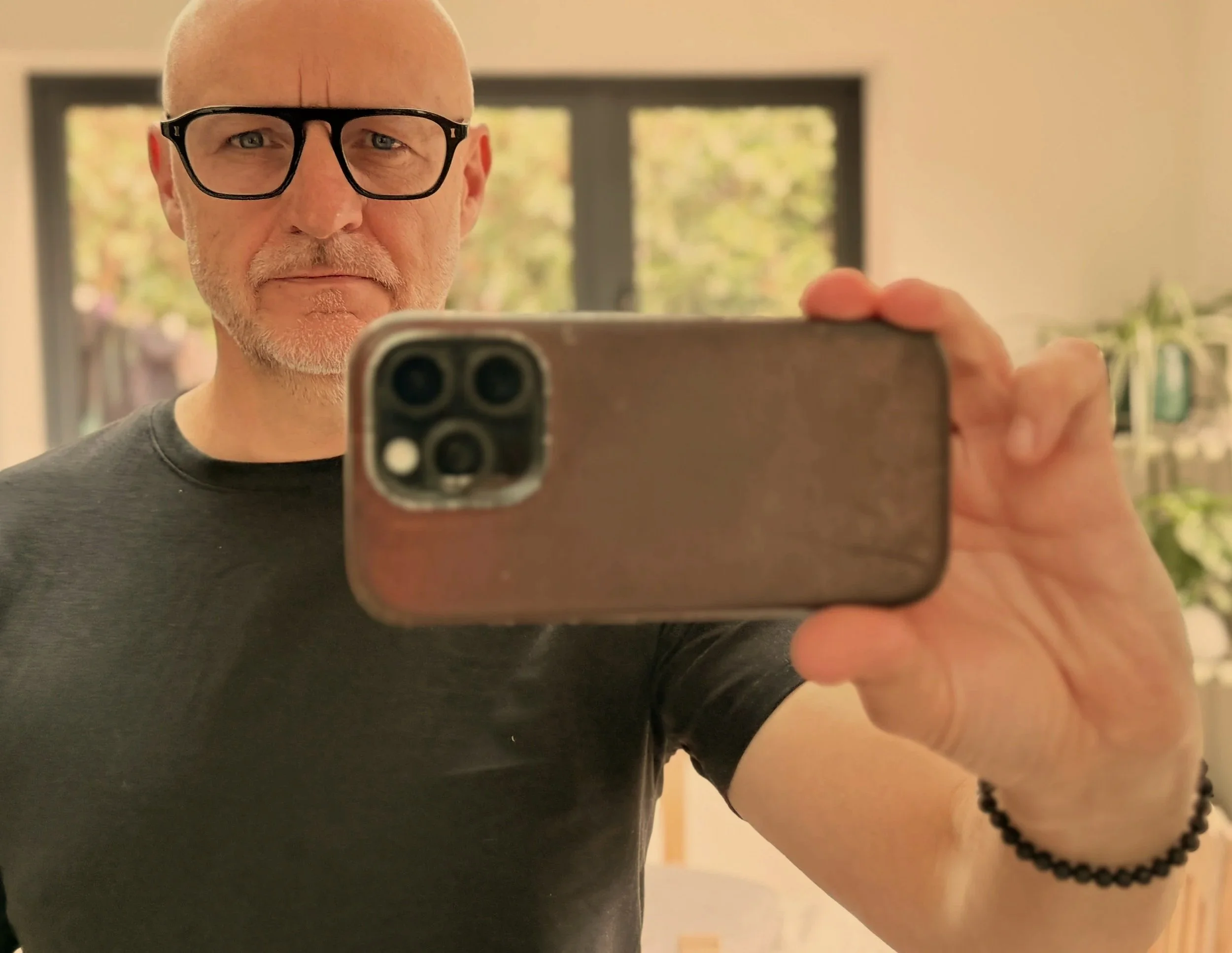 man with a beard and glasses taking a selfie in front of a mirror
