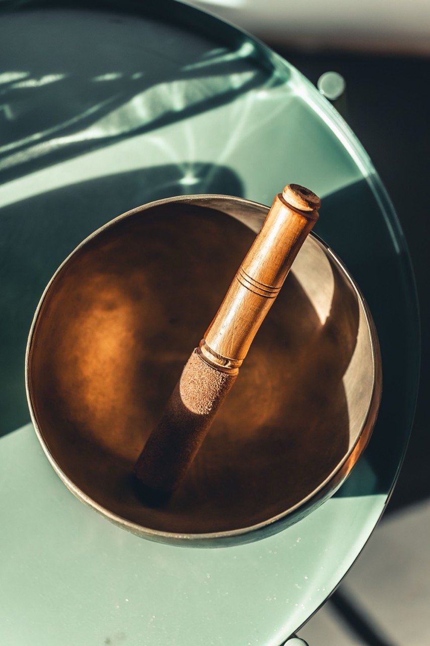 golden-sound-bowl-and-wand-sits-on-mint-table-in-sunlit-room.jpeg