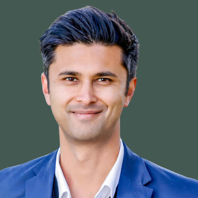 Headshot of smiling male with short black hair in green background.