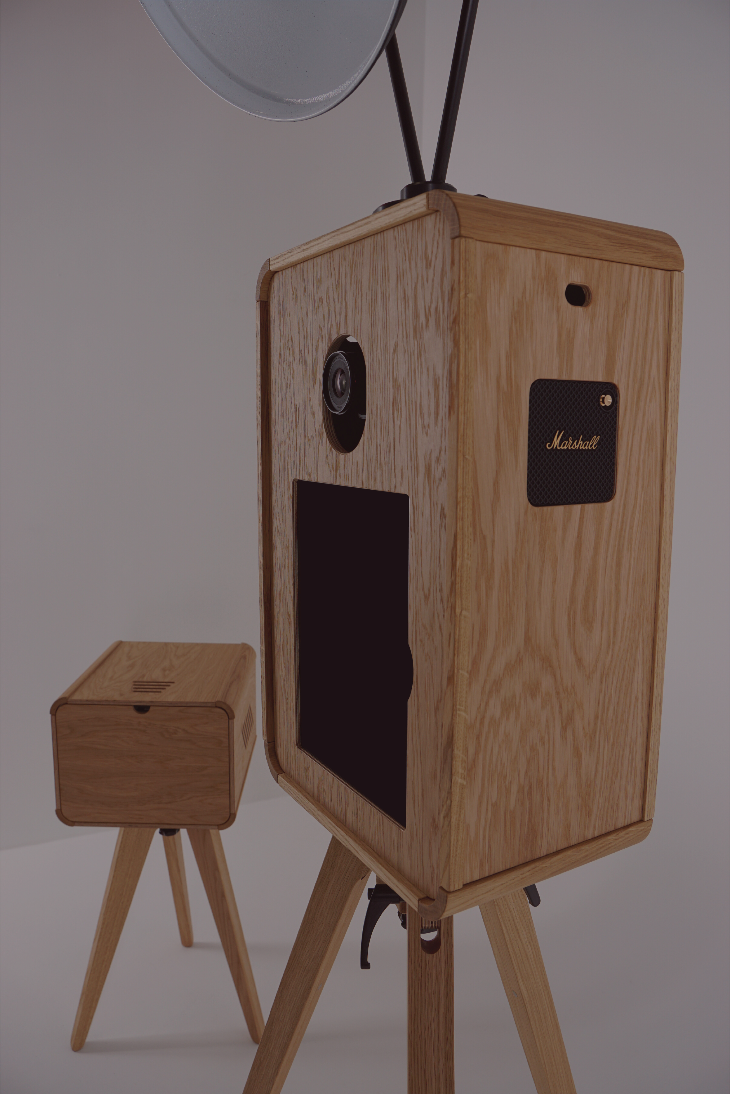 Wooden photo booth showcasing the camera, iPad and a Marshall speaker, with a matching wooden table on a tripod stand nearby.