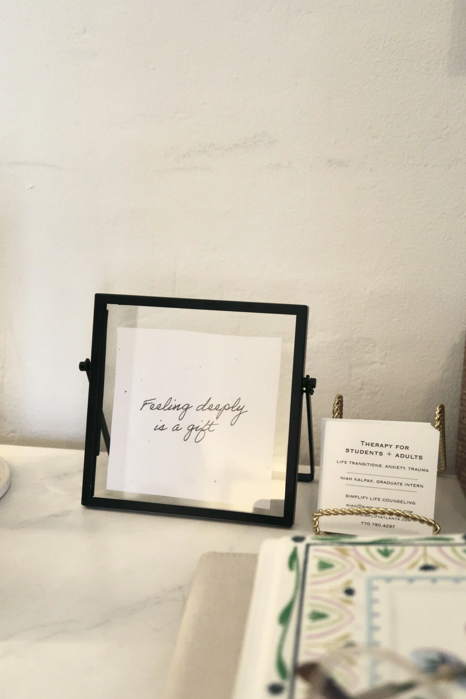 A display of framed and unframed motivational quotes and informational cards on a table. One quote reads, 'Feeling deeply is a gift,' and another mentions therapy services for students and adults.