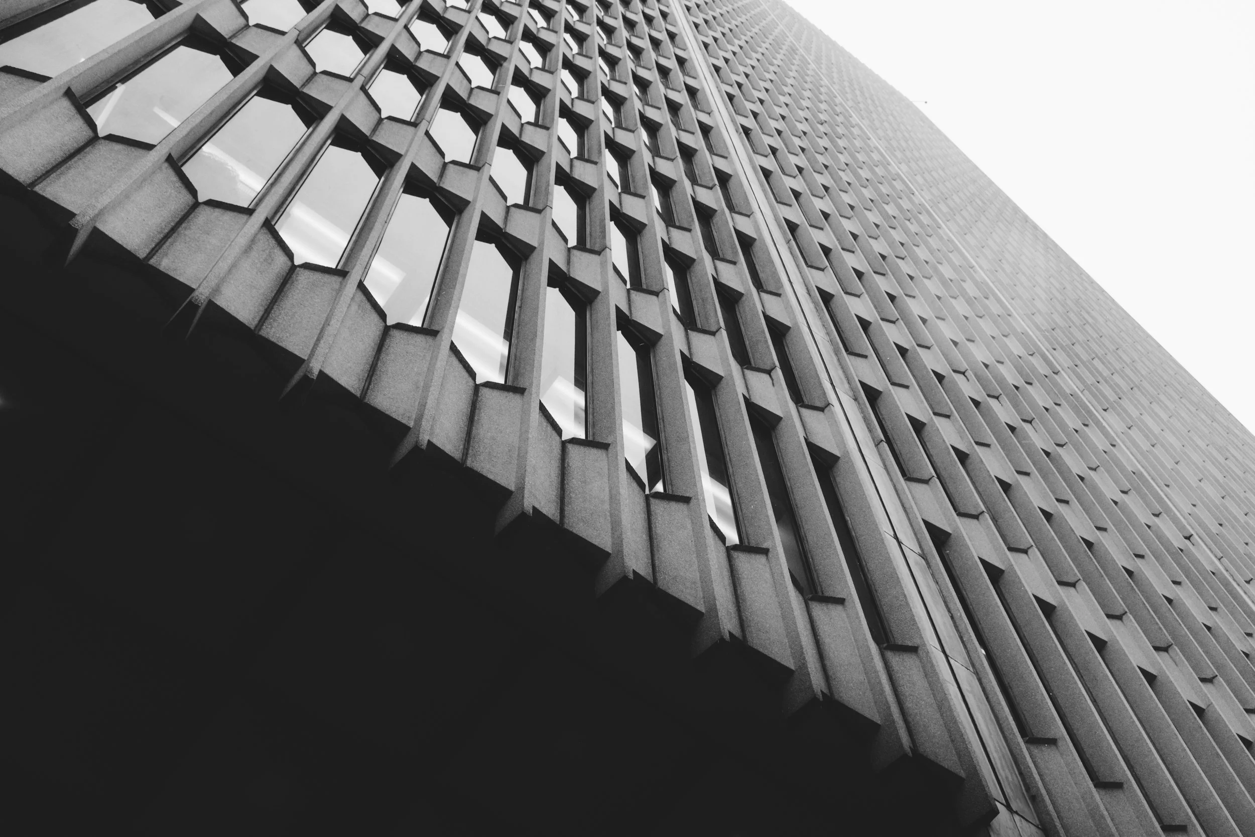 A tall modern building with a grid pattern of windows, photographed from a low angle looking up.