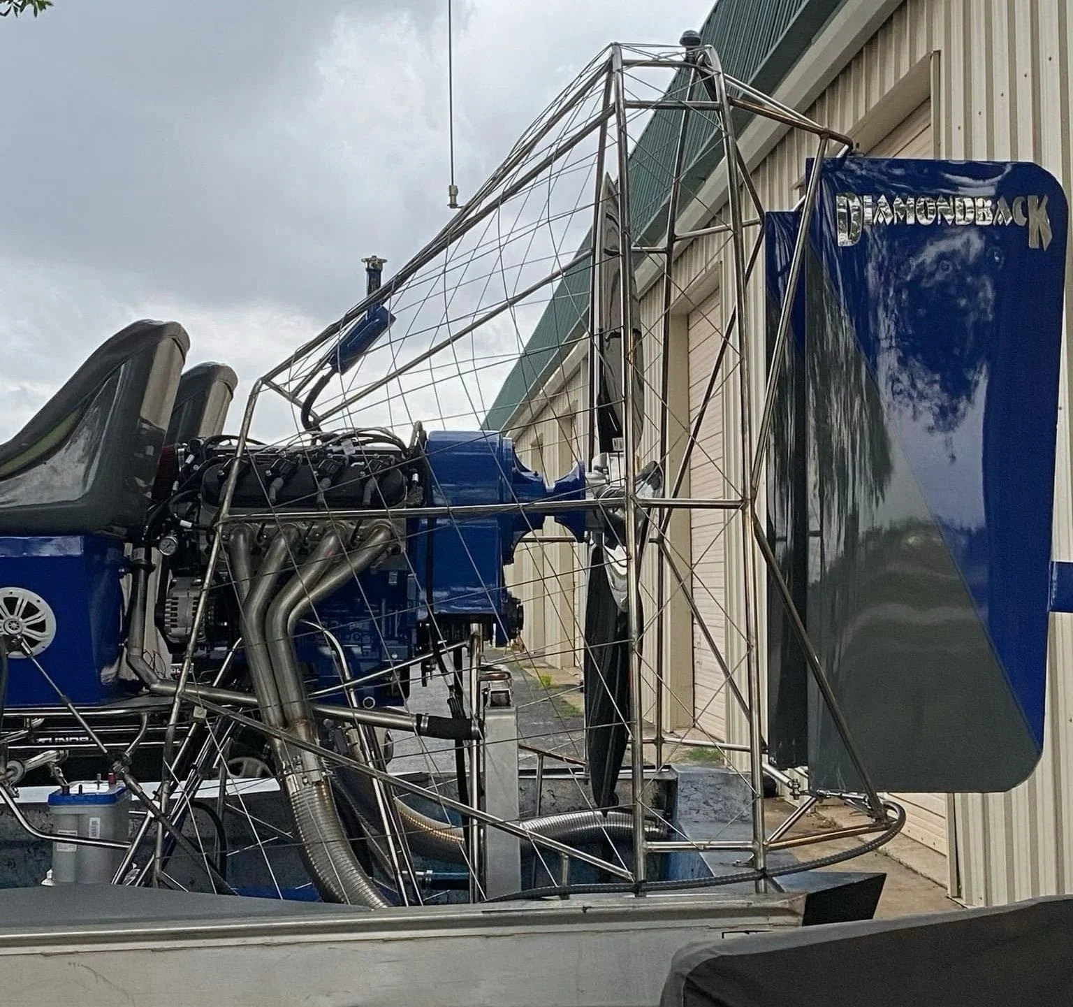 A racing helicopter with an exposed framework and blue accents parked outside a building.