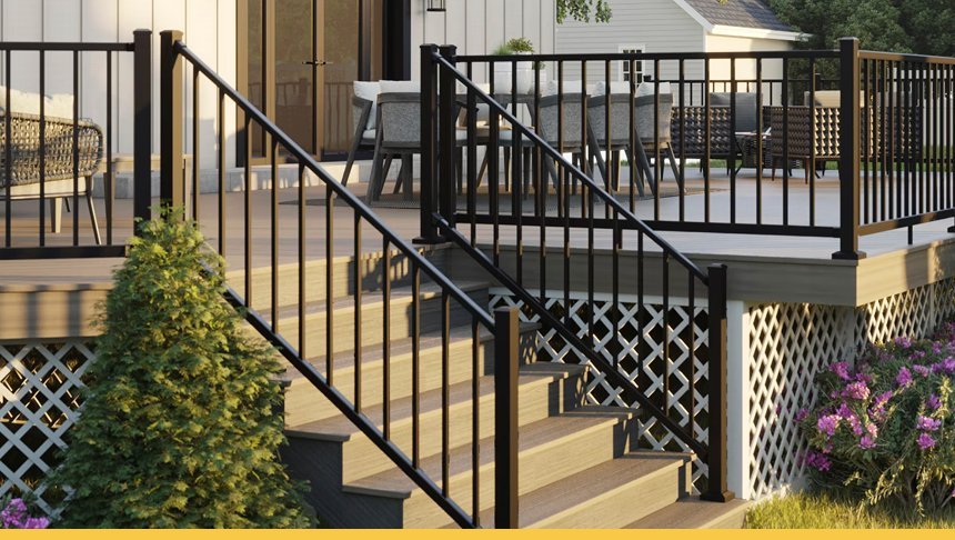 Outdoor deck with stairs and black metal railing, surrounded by garden with green bush and purple flowers.